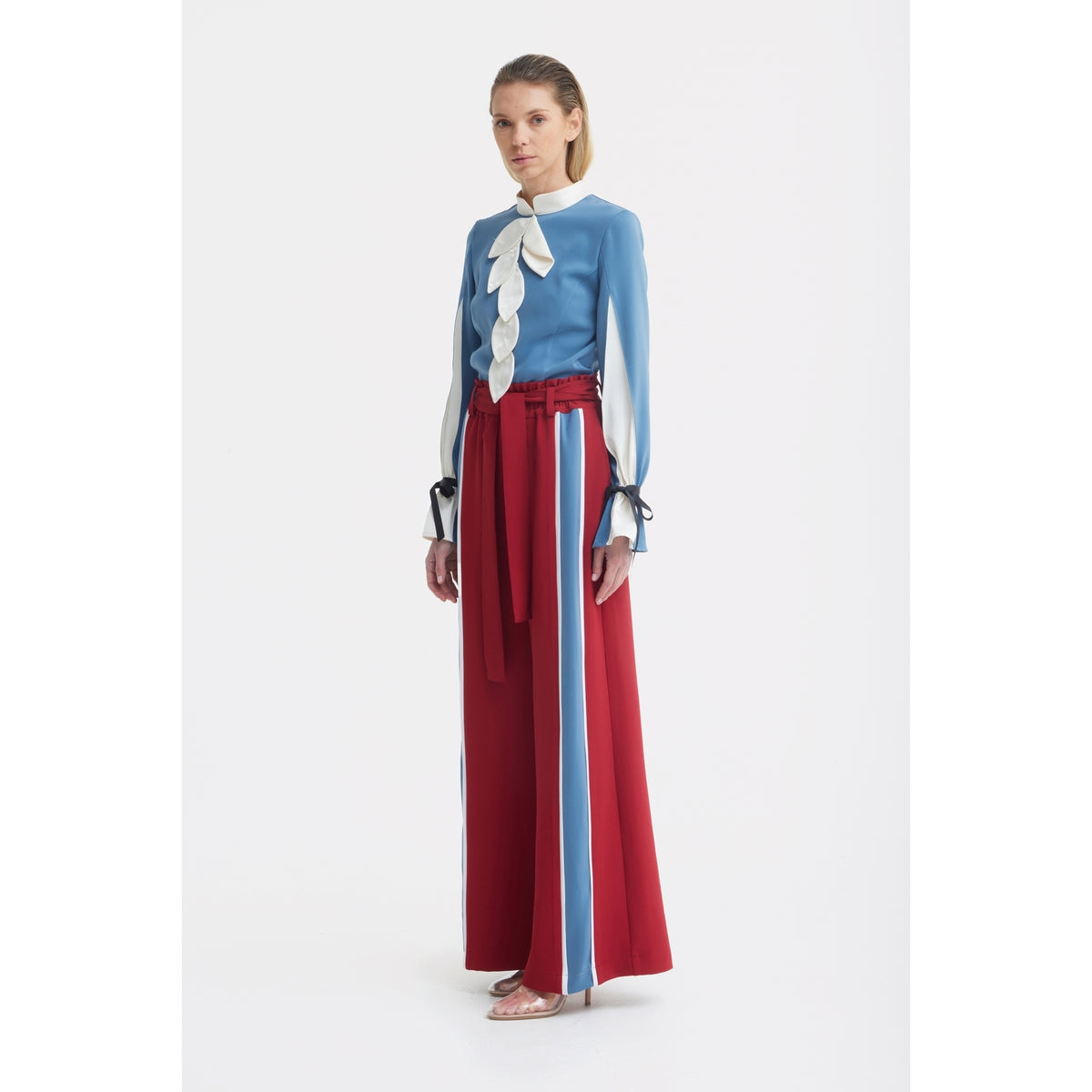 A woman stands barefoot against a white background wearing JULIA ALLERT's belted high waist wide leg pants in burgundy.