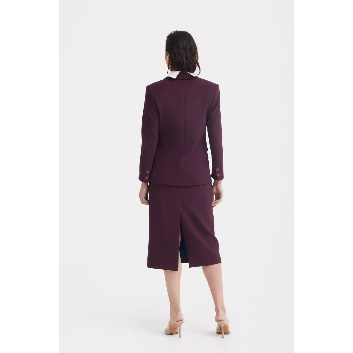 A person with medium-length dark hair wears the JULIA ALLERT Classic Tailored Double-Breasted Blazer in burgundy and a matching knee-length skirt, styled with nude heels, standing against a plain white background.