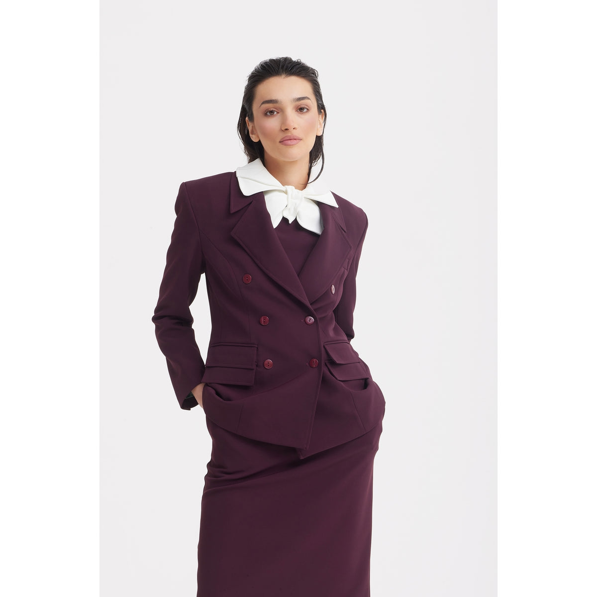A woman confidently poses against a white background in the JULIA ALLERT Classic Tailored Double-Breasted Blazer in burgundy, styled with a white oversized bow collar for a modern twist on office wear.