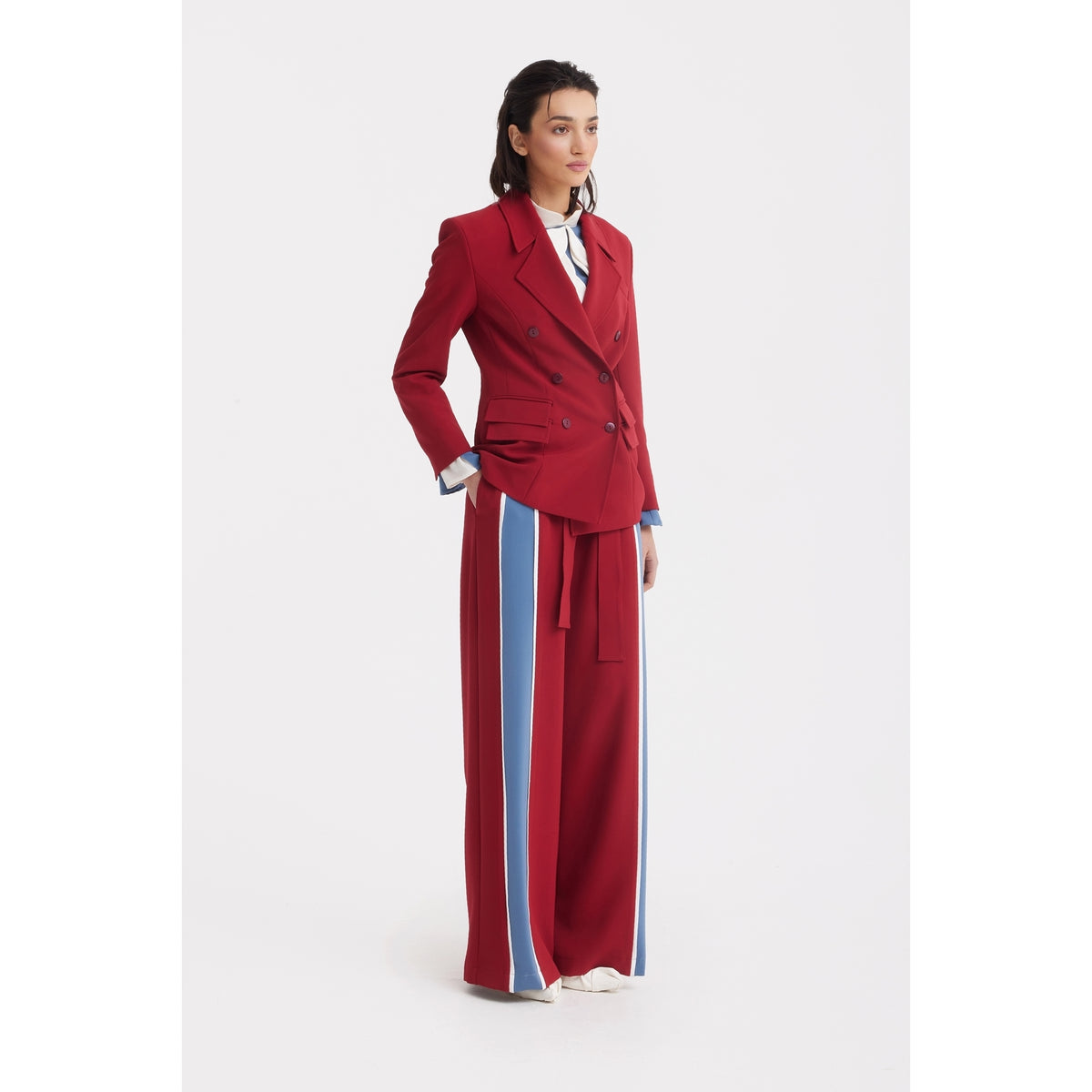 A woman wears JULIA ALLERT Belted High Waist Wide Leg Pants - Burgundy with a red double-breasted blazer, white shirt, and white shoes, standing against a plain white background.