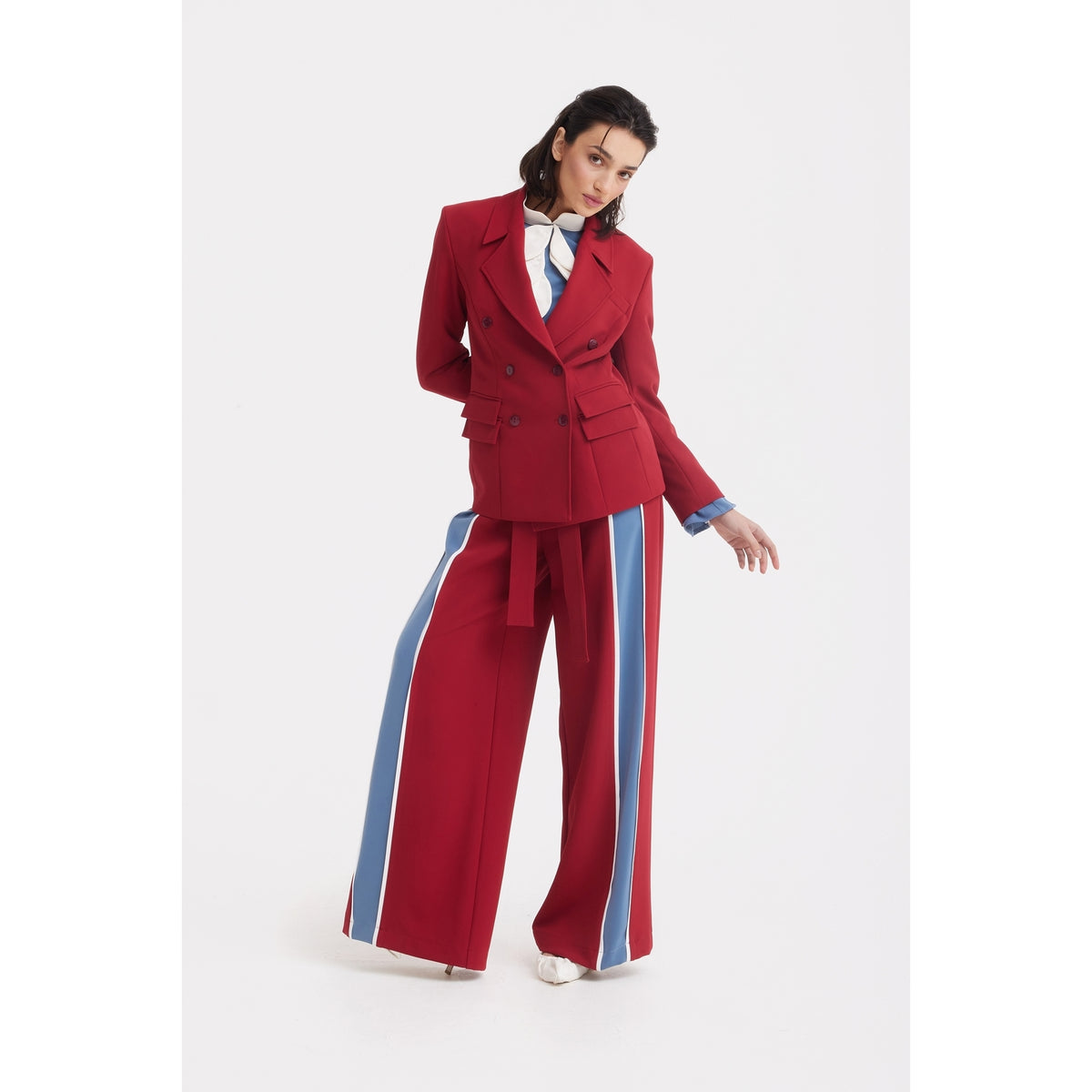 A woman poses in JULIA ALLERT Belted High Waist Wide Leg Pants - Burgundy with a red double-breasted blazer, light blue shirt, and blue tie against a white background.