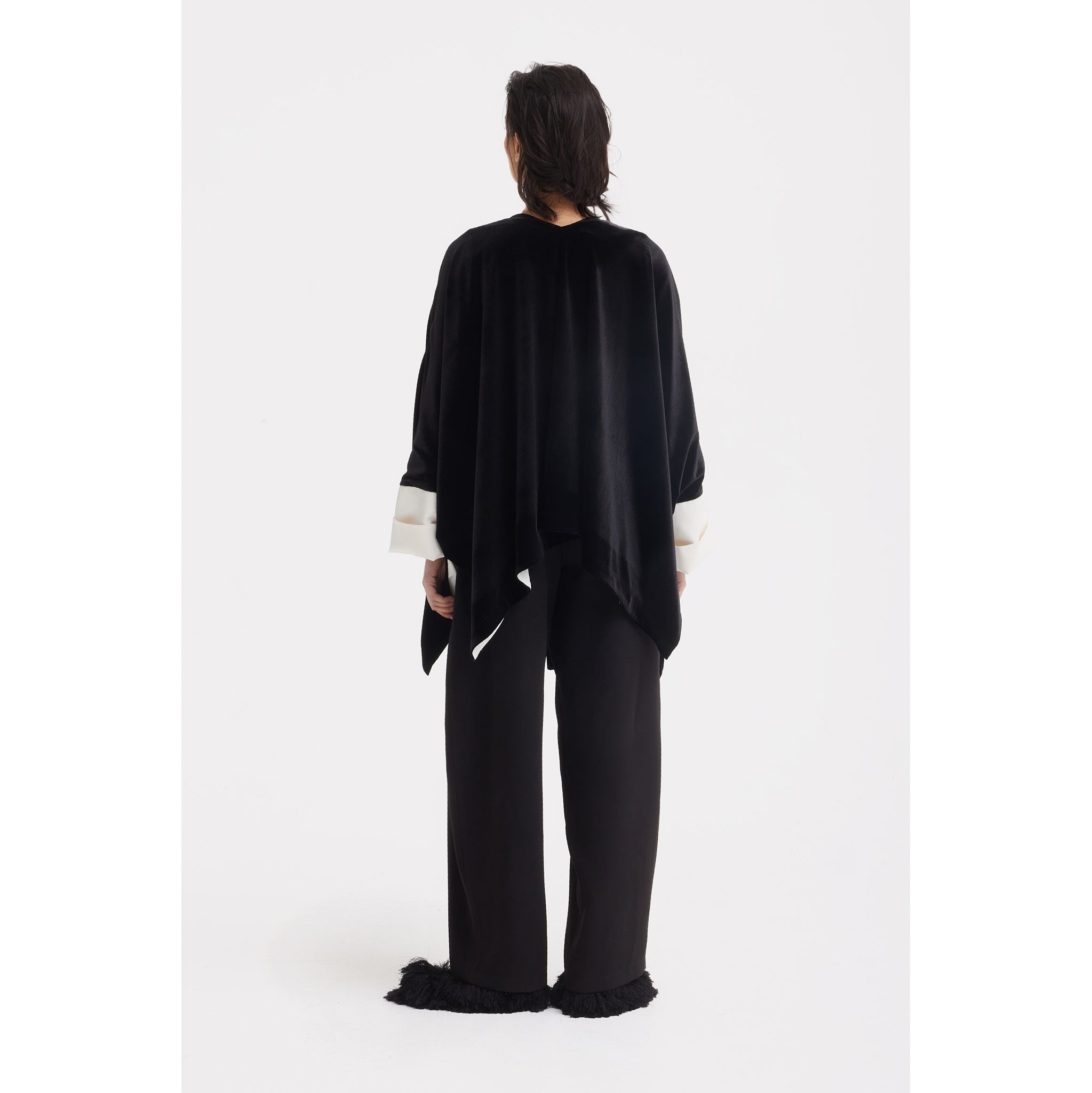 A person stands against a white background, facing away, wearing the JULIA ALLERT Loose Velvet Cape Jacket With Zip Front in black—an elegant layering piece ideal for sophisticated evening wear.