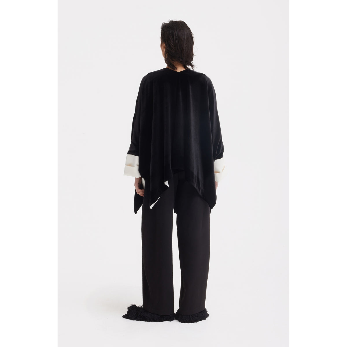A person stands against a white background, facing away, wearing the JULIA ALLERT Loose Velvet Cape Jacket With Zip Front in black—an elegant layering piece ideal for sophisticated evening wear.