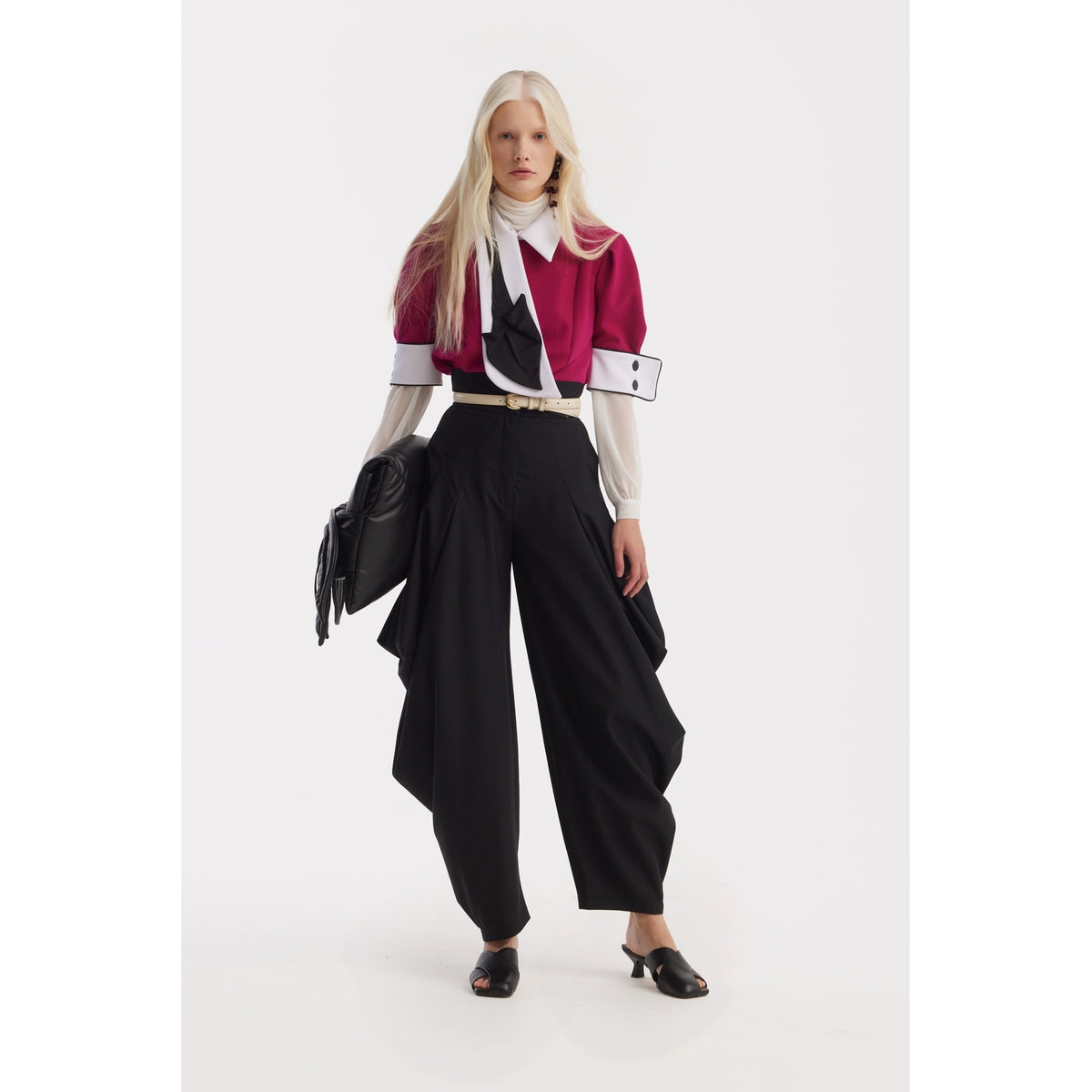 A person with long, straight blond hair models a bold outfit: a magenta cropped jacket over the JULIA ALLERT Statement Blouse With White Collar And Cuffs - Fuchsia, paired with high-waisted wide-leg black pants, black heeled mules, and a large black clutch.
