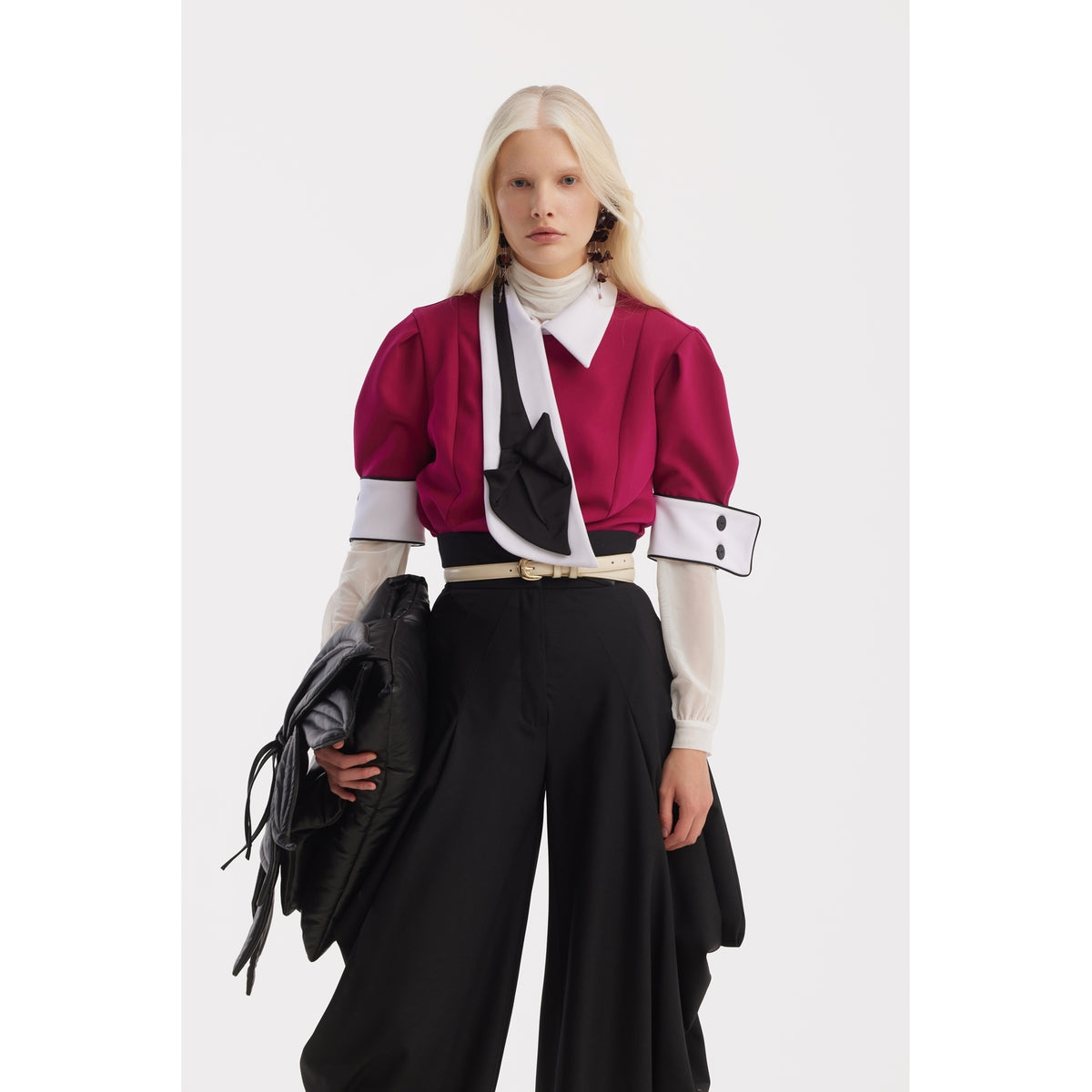 A person with long blonde hair wears a JULIA ALLERT Statement Blouse With White Collar And Cuffs in fuchsia, paired with wide black pants and a large clutch, standing against a plain white background.