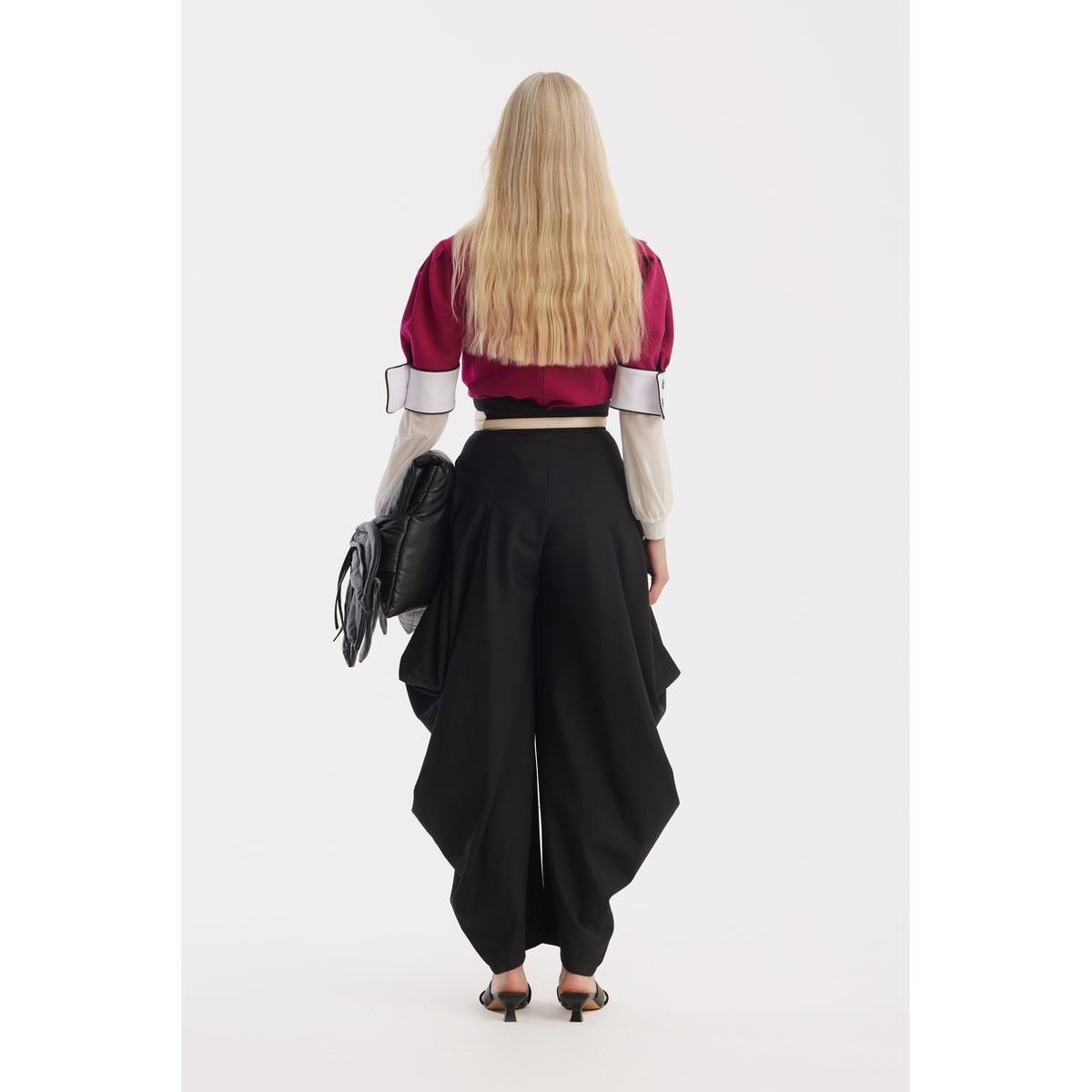 A person with long blonde hair, seen from the back, wears a JULIA ALLERT Statement Blouse With White Collar And Cuffs in fuchsia, high-waisted black wide-leg pants with draped sides, black heels, and carries a black bag.