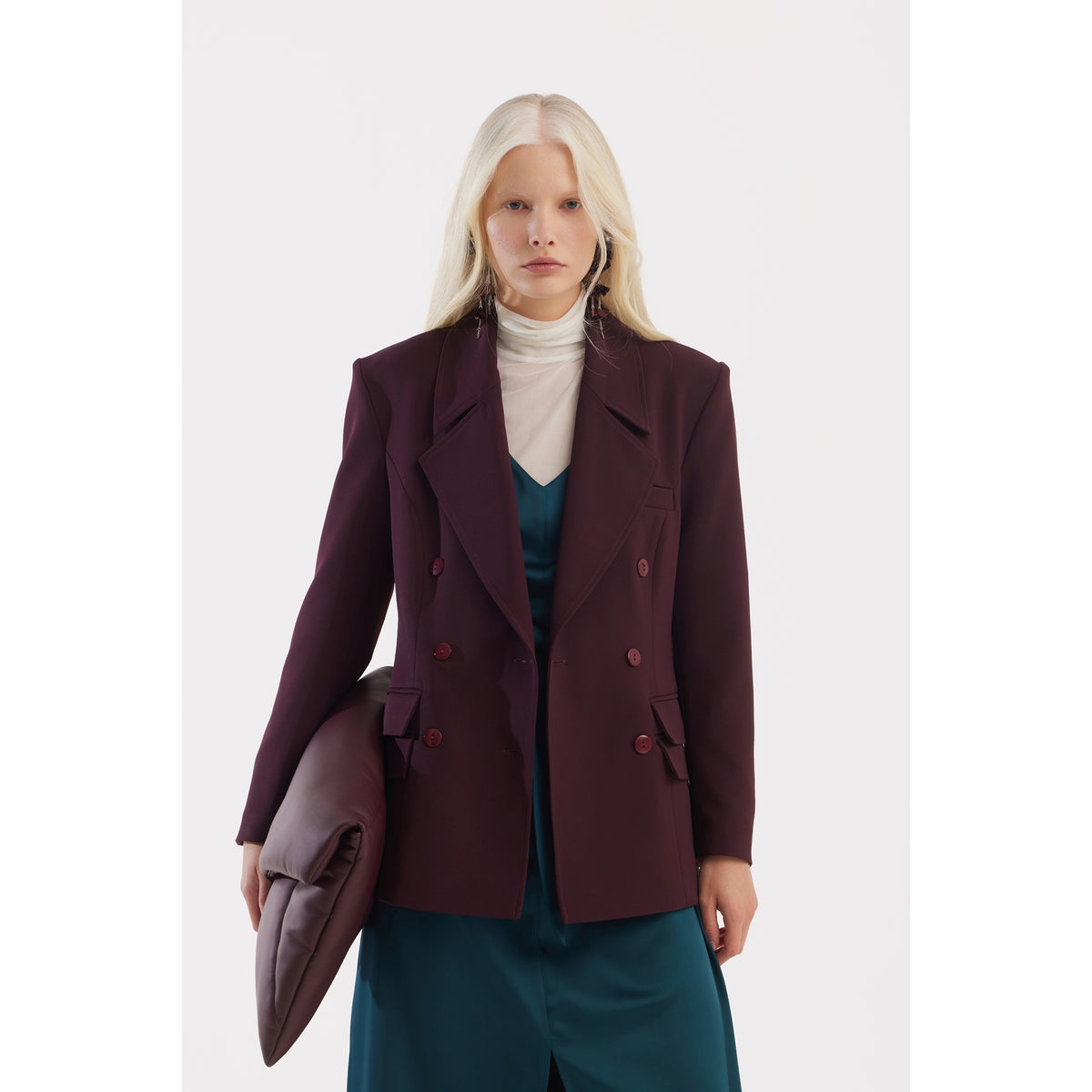 A person with long blonde hair stands against a white background, wearing the JULIA ALLERT Classic Tailored Double-Breasted Blazer in burgundy—an ideal choice for modern office wear.