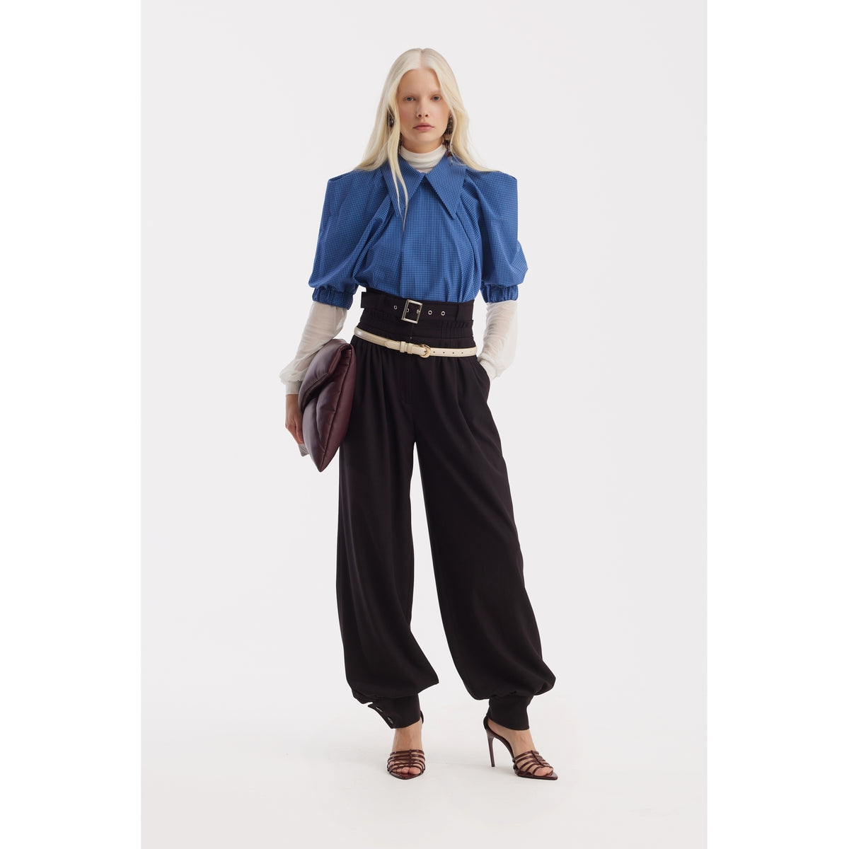 A person with long blonde hair wears the JULIA ALLERT Designer Plaid Puff Sleeve Blouse in blue over a white turtleneck, paired with high-waisted black pants, strappy heels, and a large brown clutch against a white background.