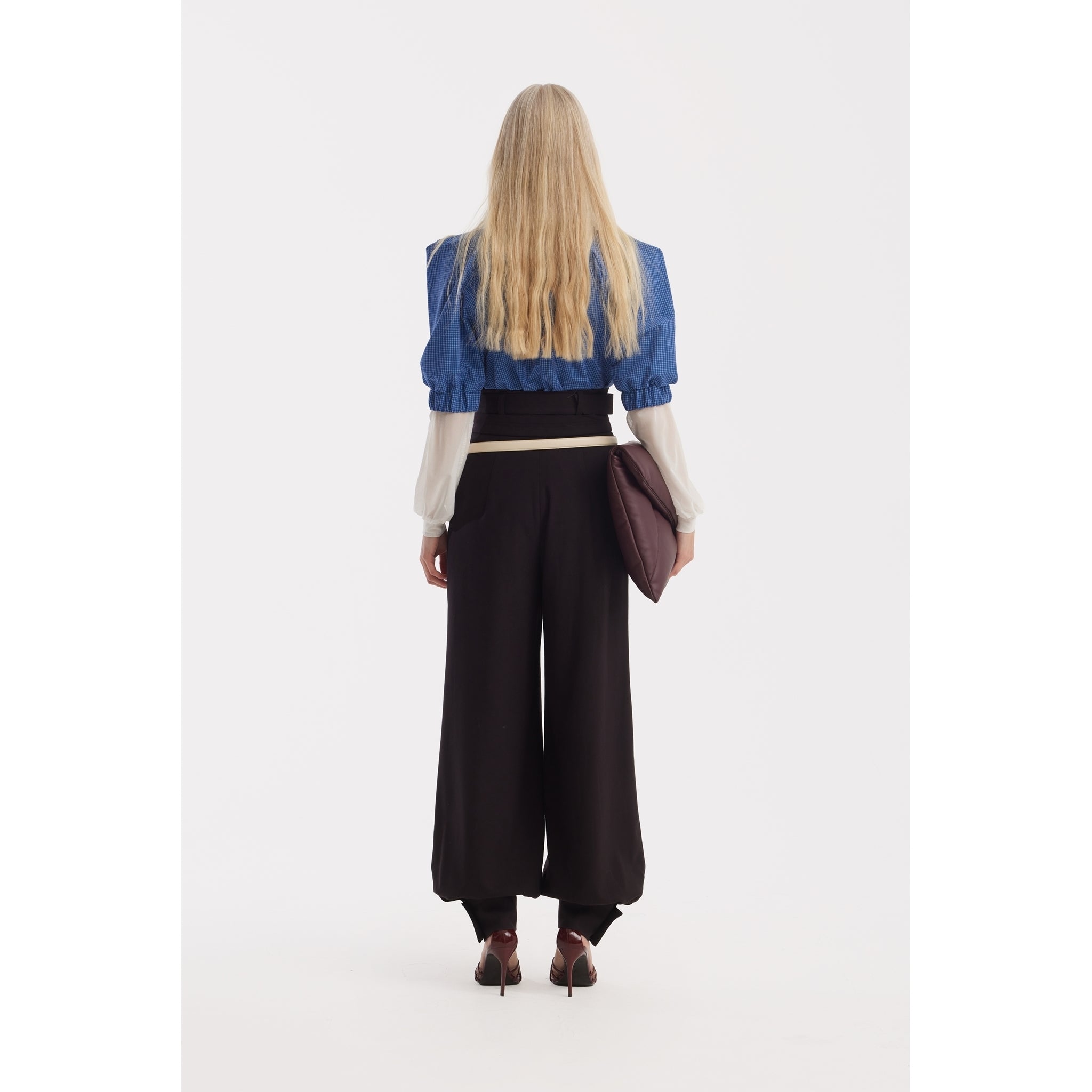 A person with long blonde hair, seen from behind, wears a JULIA ALLERT Designer Plaid Puff Sleeve Blouse in blue, black wide-leg pants, and high heels, holding a large dark brown clutch bag against a white background.