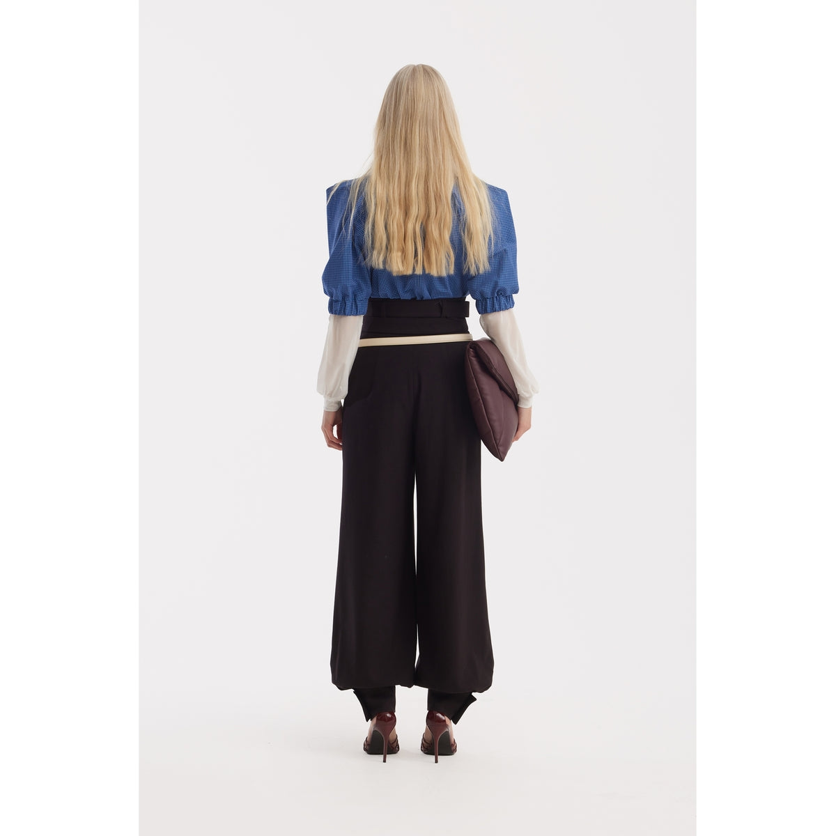 A person with long blonde hair, seen from behind, wears a JULIA ALLERT Designer Plaid Puff Sleeve Blouse in blue, black wide-leg pants, and high heels, holding a large dark brown clutch bag against a white background.