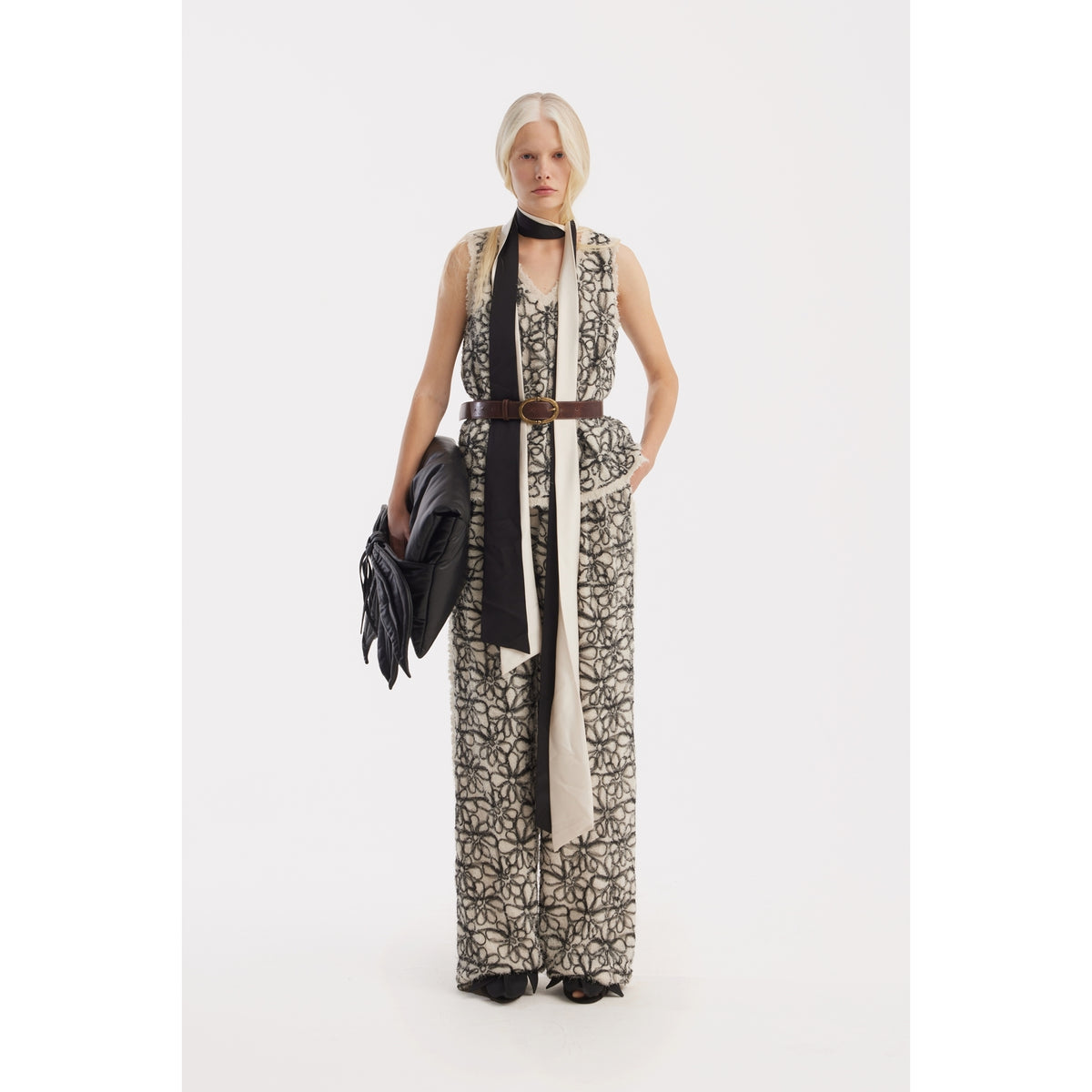 A woman stands against a white background wearing JULIA ALLERT Elastic Waist Abstract Textured Wide Pants in ivory, styled with a black and beige neck scarf, holding a black clutch, and has one hand in her pocket.