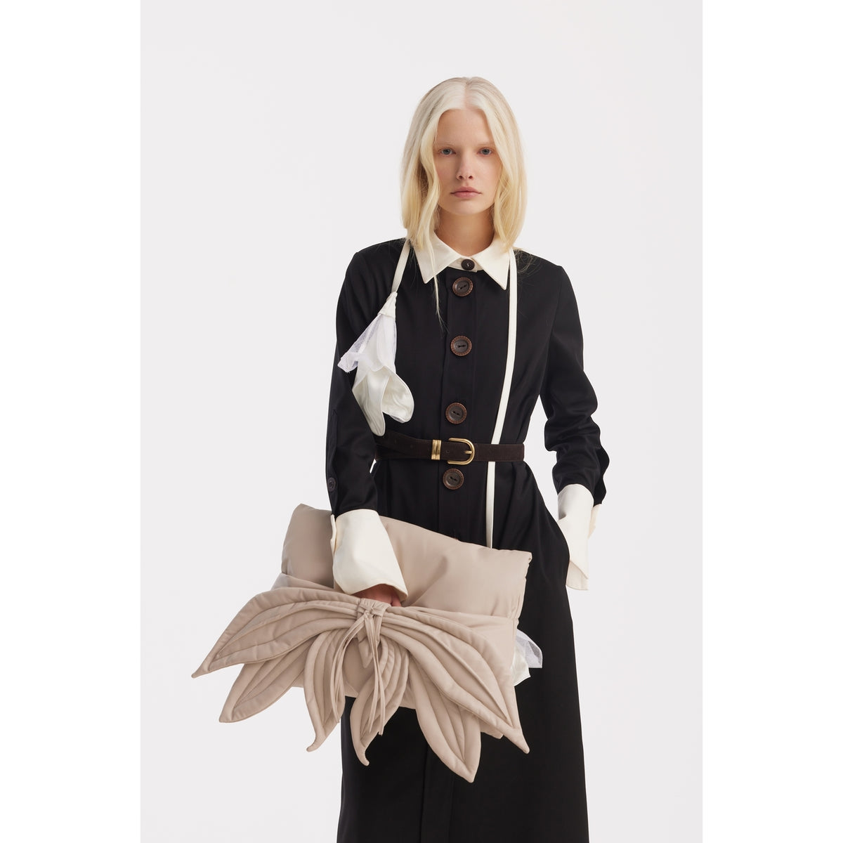 A woman with long blonde hair wears the JULIA ALLERT Monochrome Midi Shirt Dress - Black &amp; White, featuring a white collar and cuffs. She holds a large beige flower-shaped clutch, standing against a plain white background.