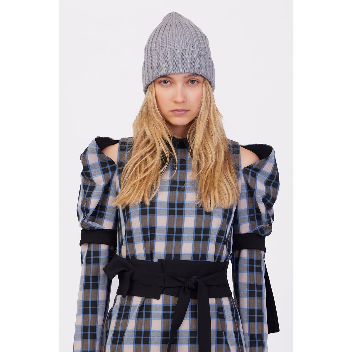 A woman with long blonde hair wears the JULIA ALLERT Stylish Cold Shoulder Long Sleeve Dress With Belt in Blue Check, featuring puffed sleeves and cut-outs, along with a gray knit beanie, against a plain white background.