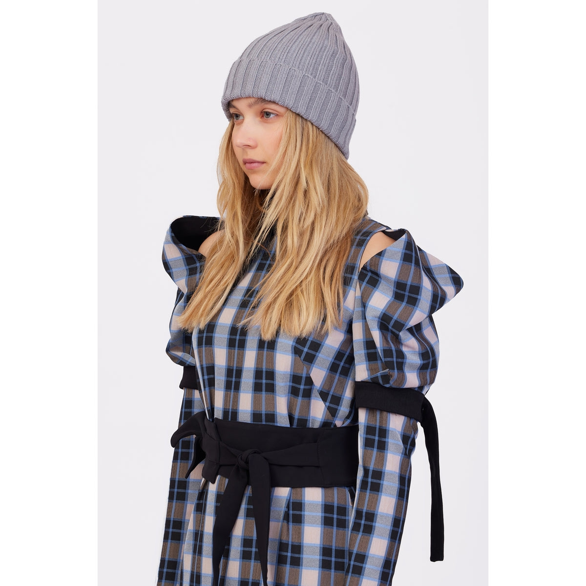 A woman with long blonde hair wears the JULIA ALLERT Stylish Cold Shoulder Long Sleeve Dress With Belt in blue check and a gray knit beanie, standing against a plain white background.