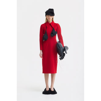 A woman wears the JULIA ALLERT Solid Formal Midi Dress in red, paired with black fuzzy slippers and a dramatic hat with a fabric veil. She accessorizes with a sculptural neckpiece and holds a balloon-like object against a white backdrop.