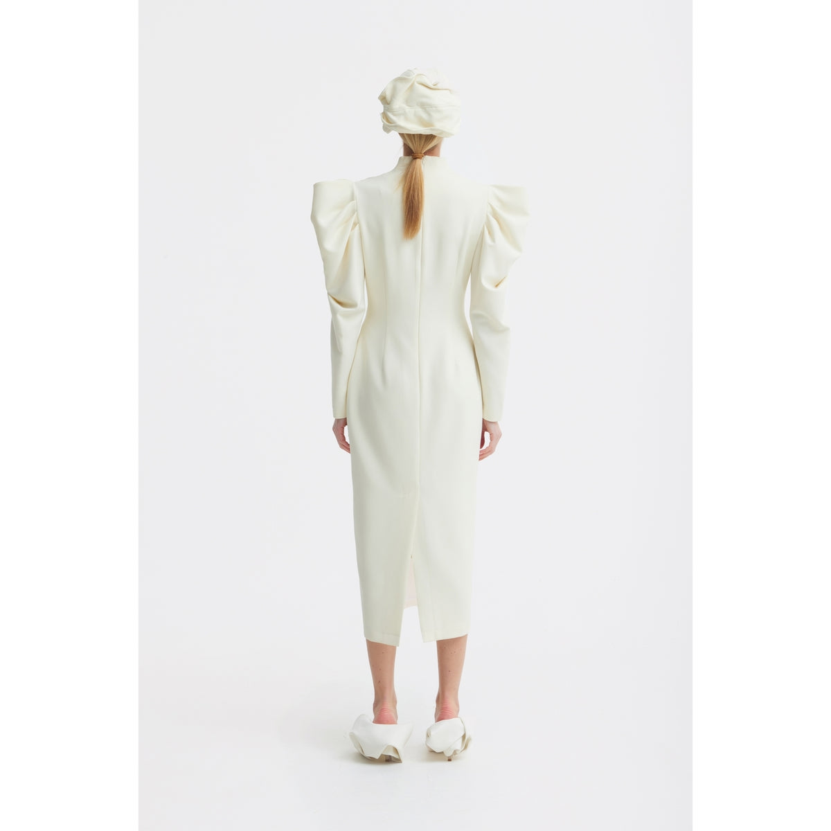 A person with long hair is seen from behind wearing the JULIA ALLERT Crepe Midi Dress With Statement Sleeves in ivory, paired with a matching hat and white shoes, set against a plain white background.