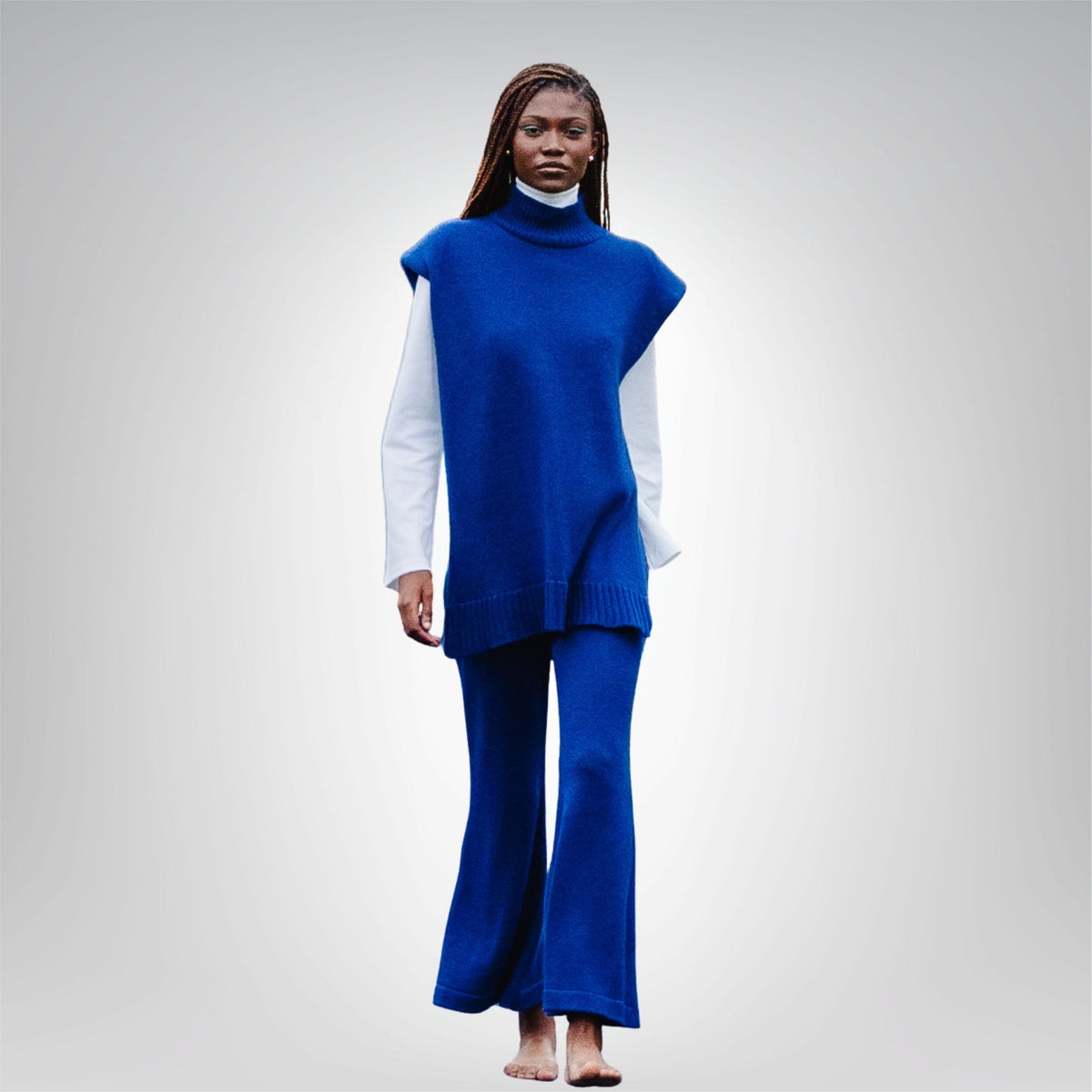 Person wearing a blue sleeveless top and pants set on a gray background