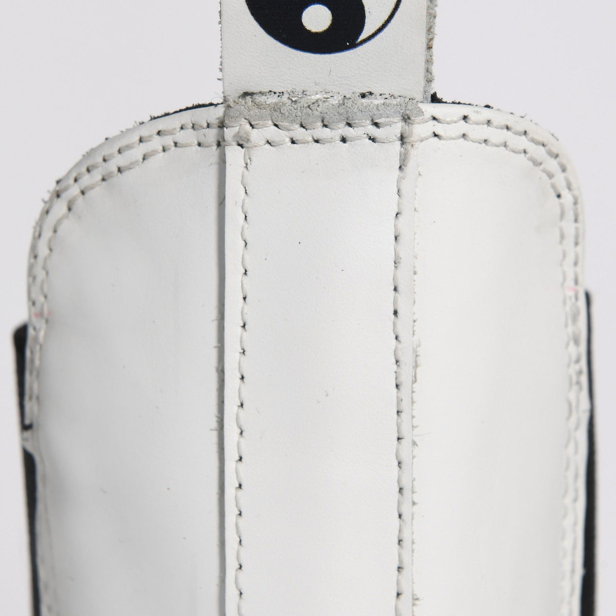 Close-up of a white leather glove with stitching detail on a light gray background