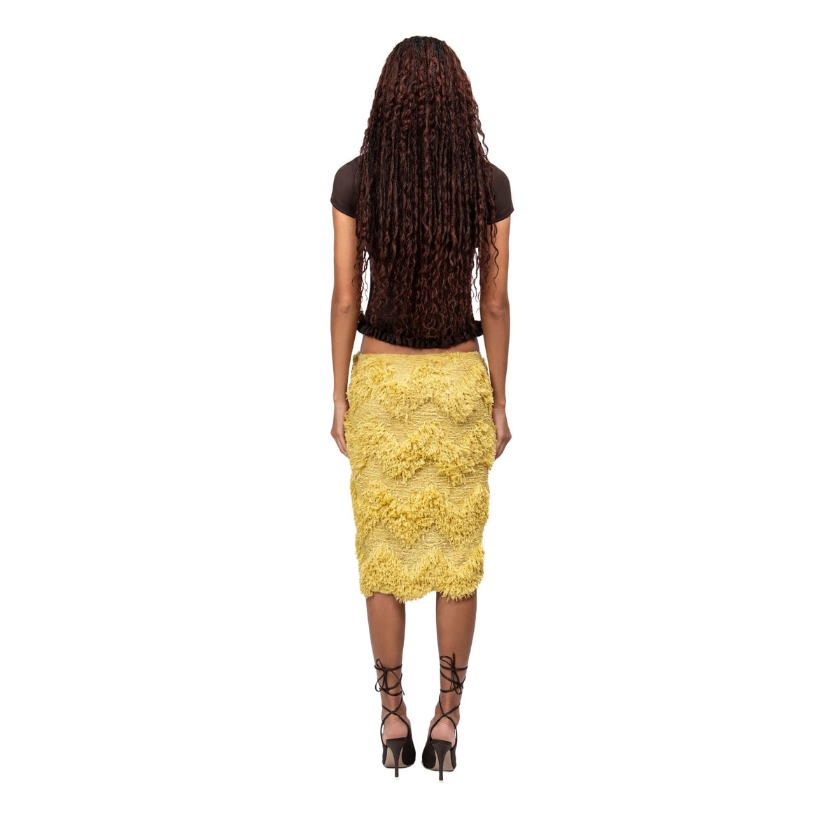 Woman wearing a yellow textured skirt and black top on a white background