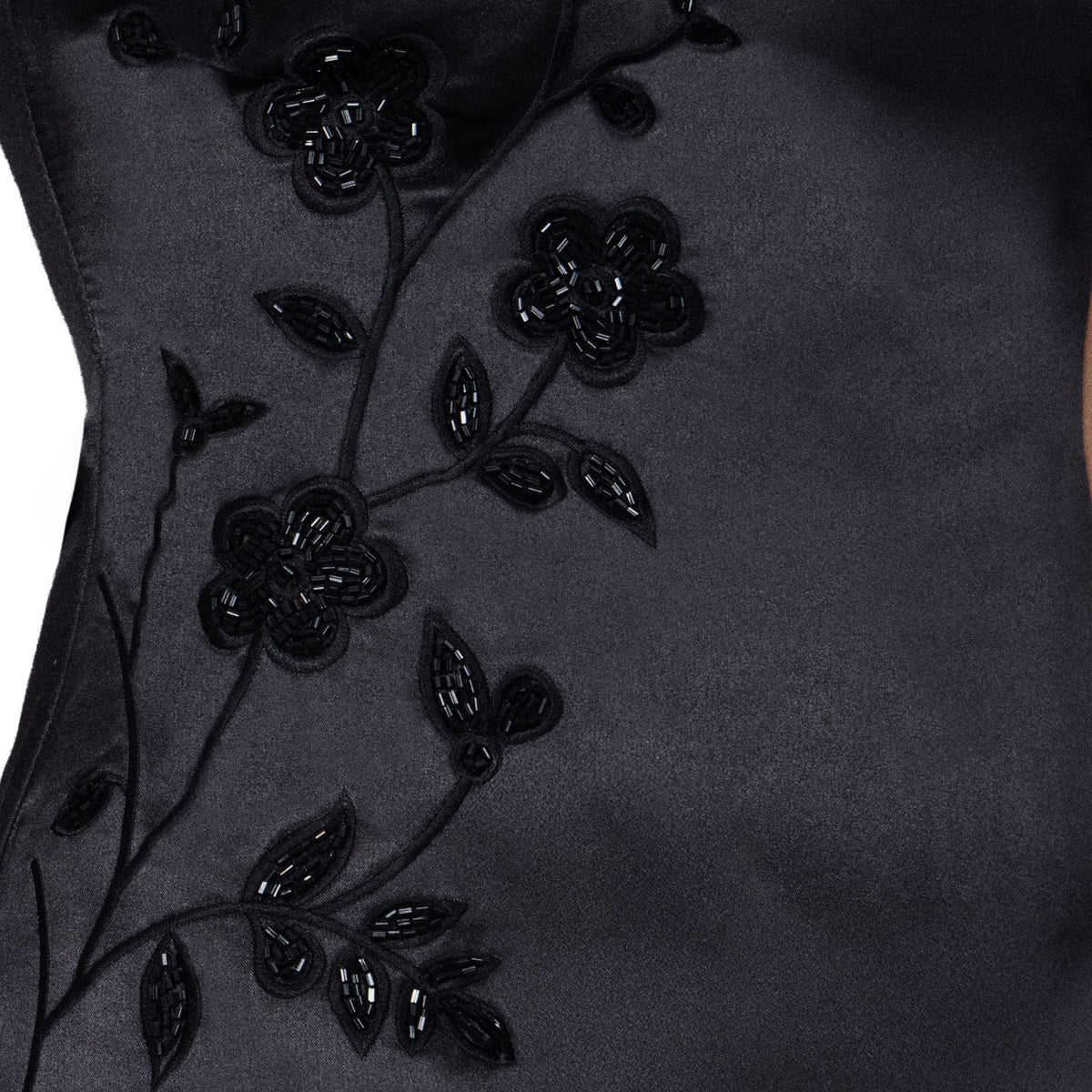 Close-up of the SELF-ADORE Fleur Luxe Satin-Feel Mini Dress, showcasing black fabric with floral embroidery and beadwork—intricate flowers and leaves create an elegant, textured design.