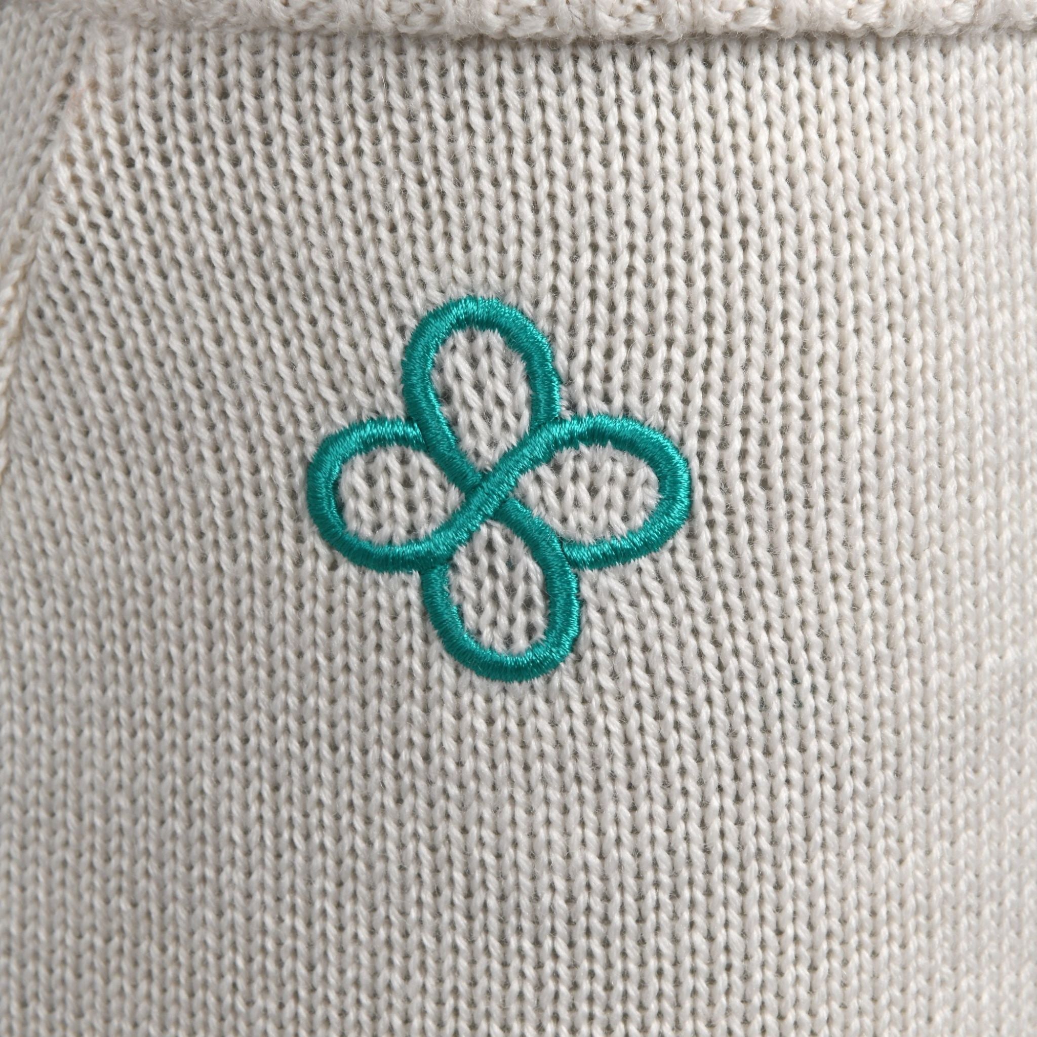 Teal embroidered flower on a beige fabric background