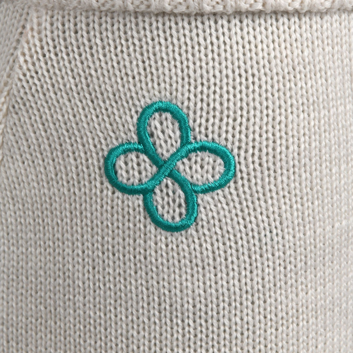 Teal embroidered flower on a beige fabric background