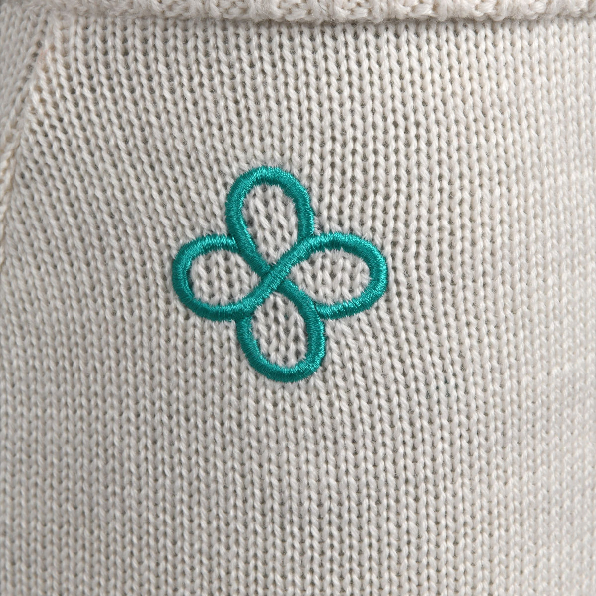Teal embroidered flower on a beige fabric background