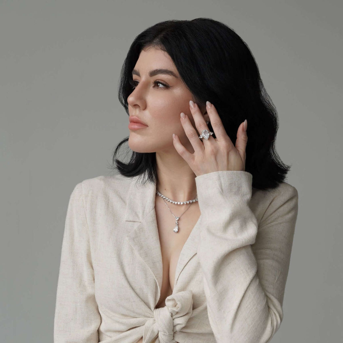 Woman wearing jewelry against a neutral background