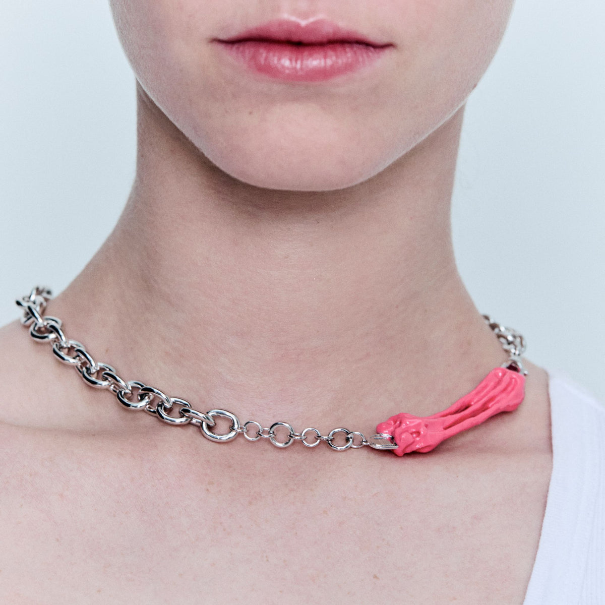 Necklace with a pink decorative element worn by a person on a light background