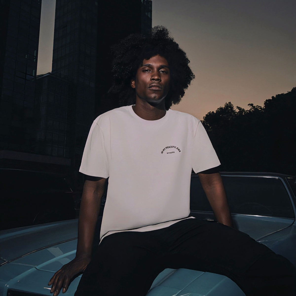 Man sitting on a car at night with a dark background