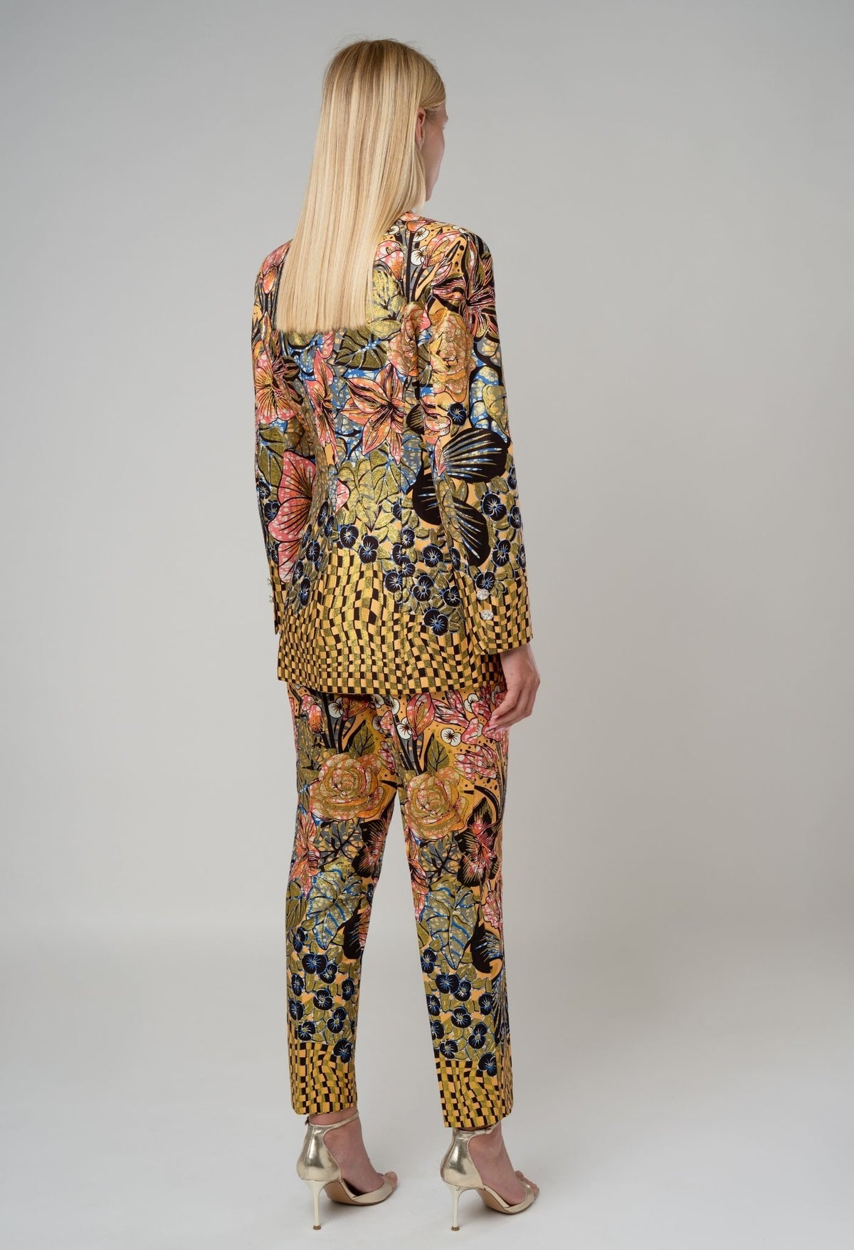 Woman wearing a colorful patterned outfit on a plain background