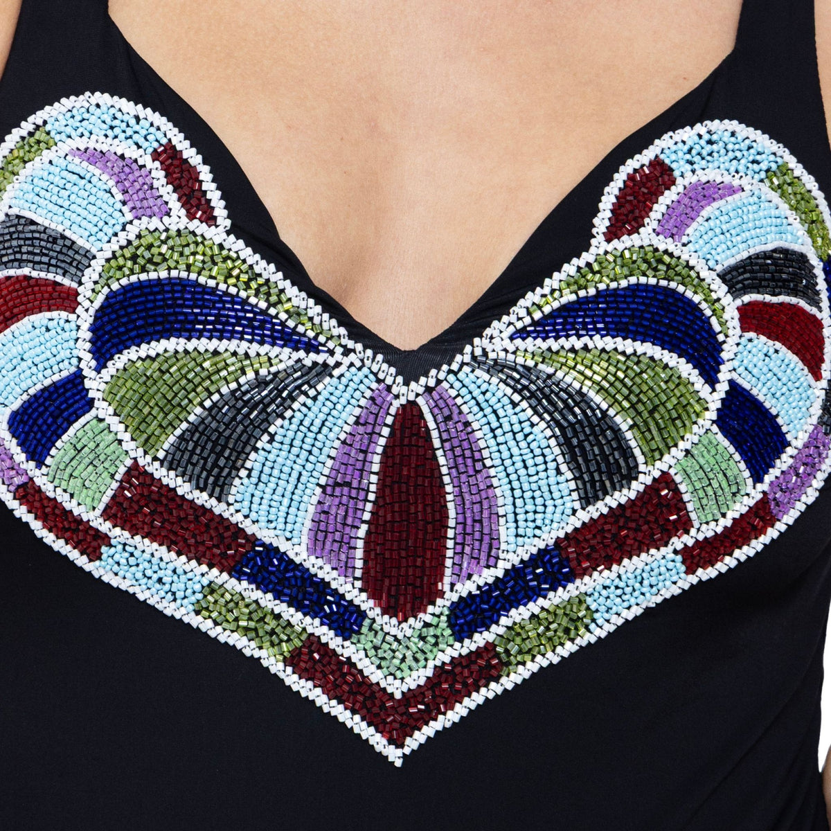 Close-up of the SELF-ADORE Amor Hand-Beaded Embellished One-Piece Swimsuit in black, featuring a hand-beaded heart detail on the chest with colorful sections of blue, green, purple, red, and white beads.