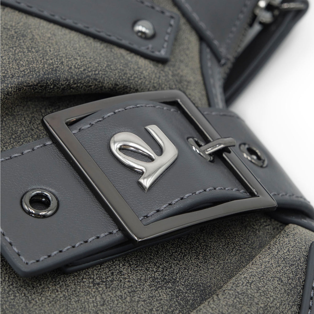Close-up of a gray leather bag with a metal buckle and logo.