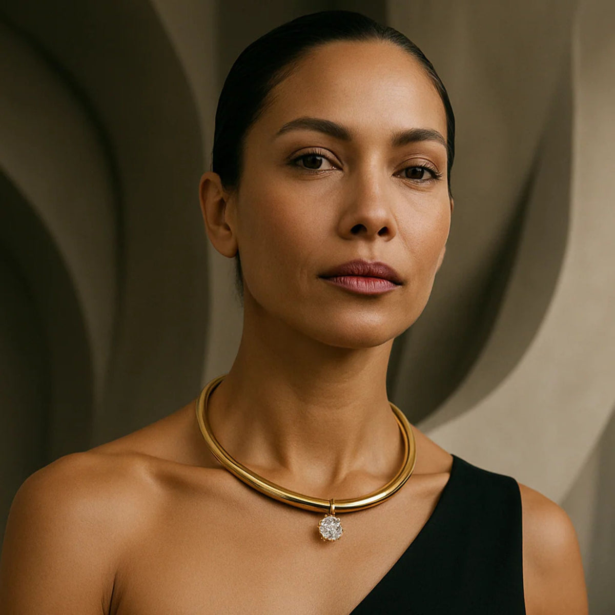 Woman wearing a gold necklace with a diamond pendant against a neutral background