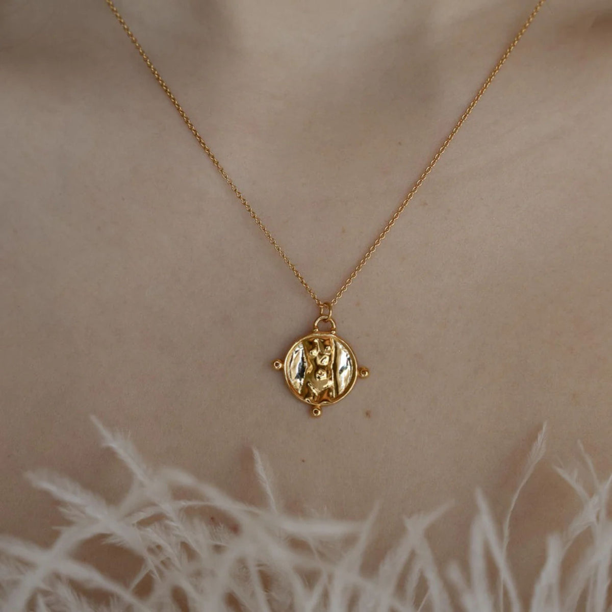 Gold necklace with a pendant on a person&#39;s neck against a neutral background