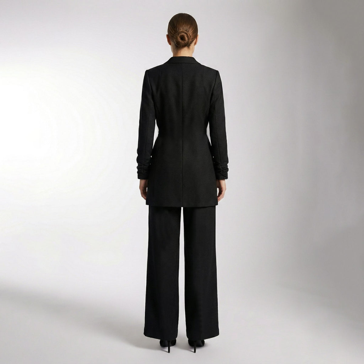 Person wearing a black suit on a plain background