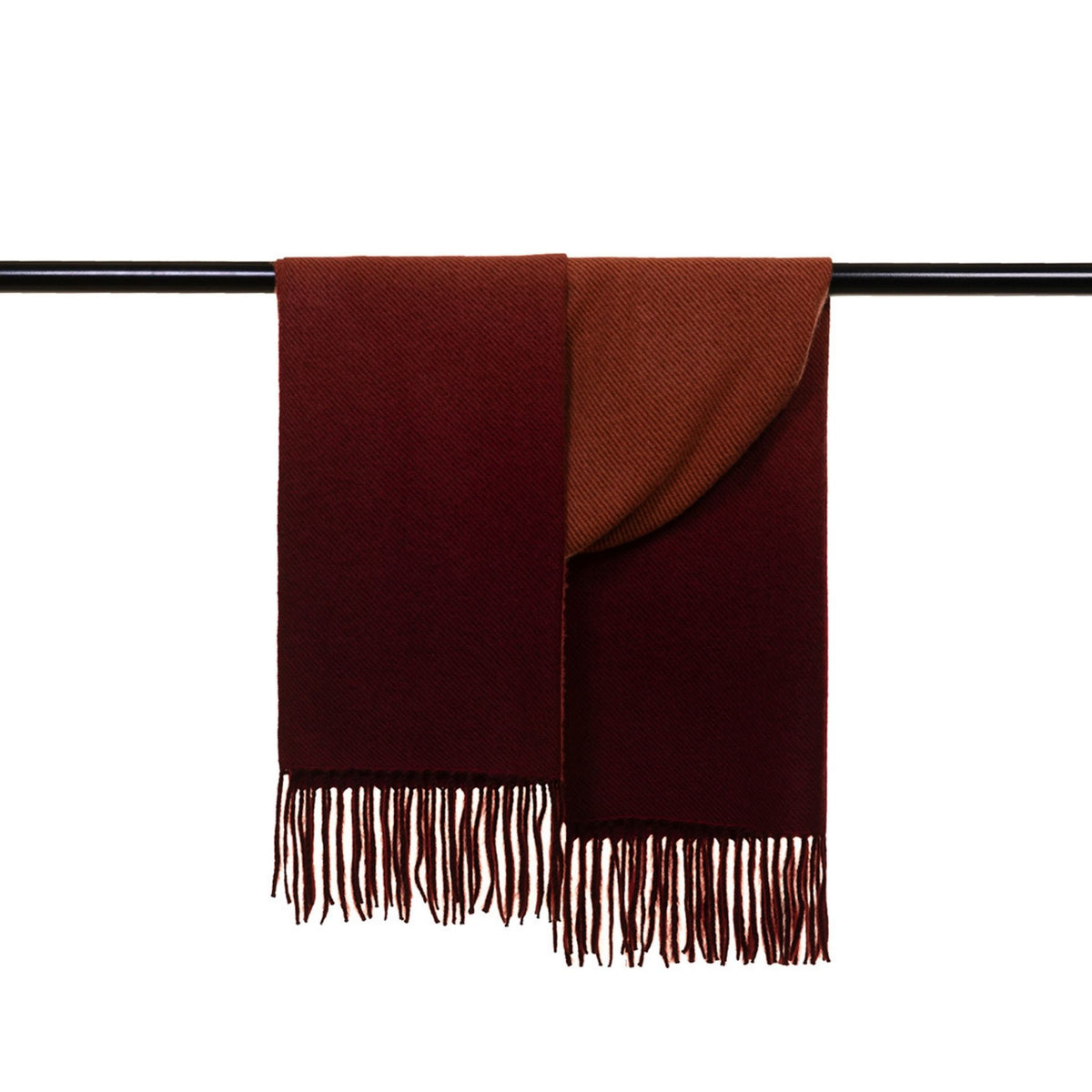 The OO-TO Standard length Fringed Ombre Scarf in wine and rust features soft texture and fringe tassels at both ends, hanging elegantly over a black rod. Handcrafted in Nepal.