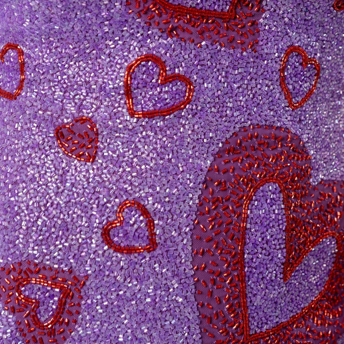 Close-up of the SELF-ADORE Lust Hand-Beaded Embellished Mini Dress, featuring a textured purple surface adorned with small beads and outlined red heart shapes in various sizes.