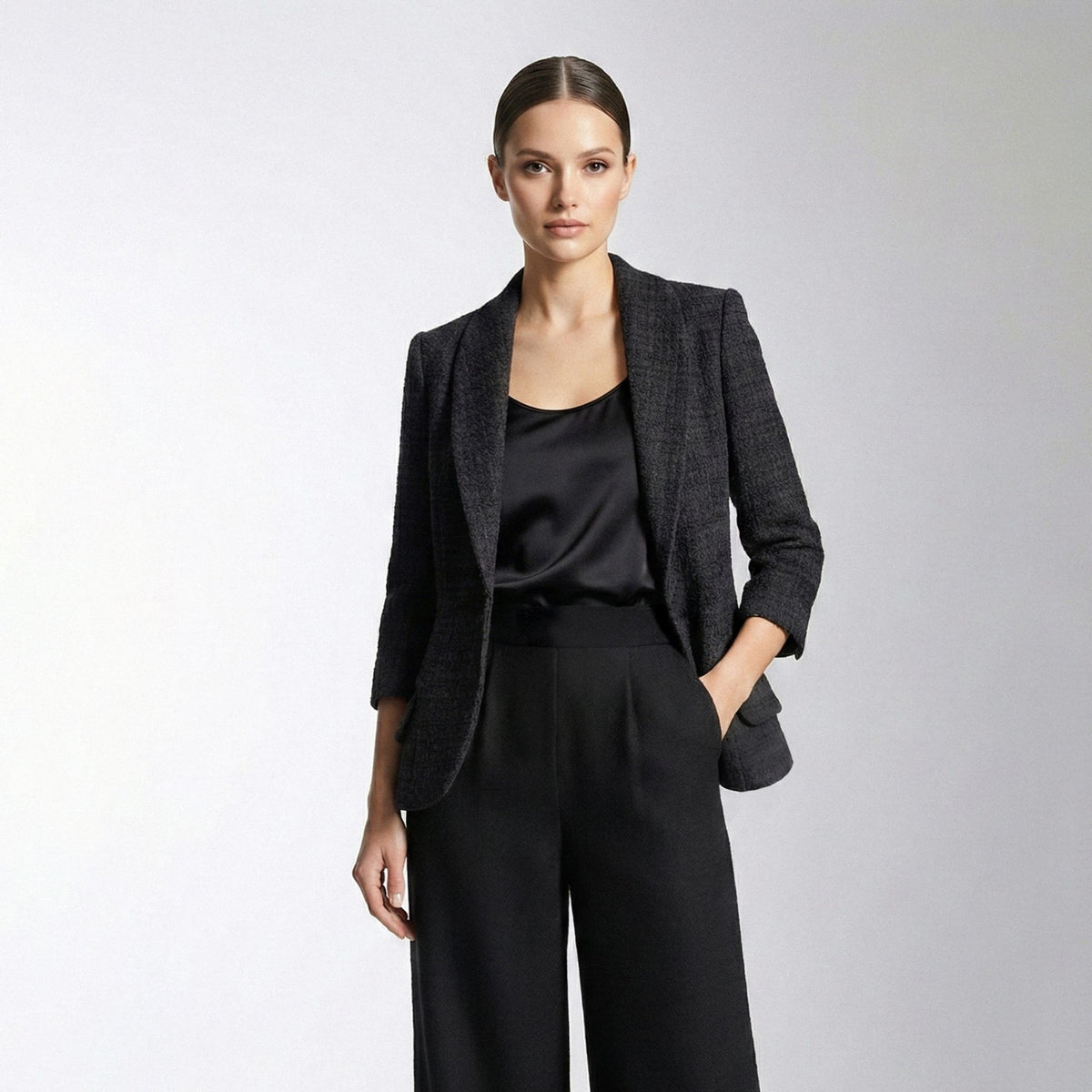 Woman wearing a black blazer and pants on a light gray background
