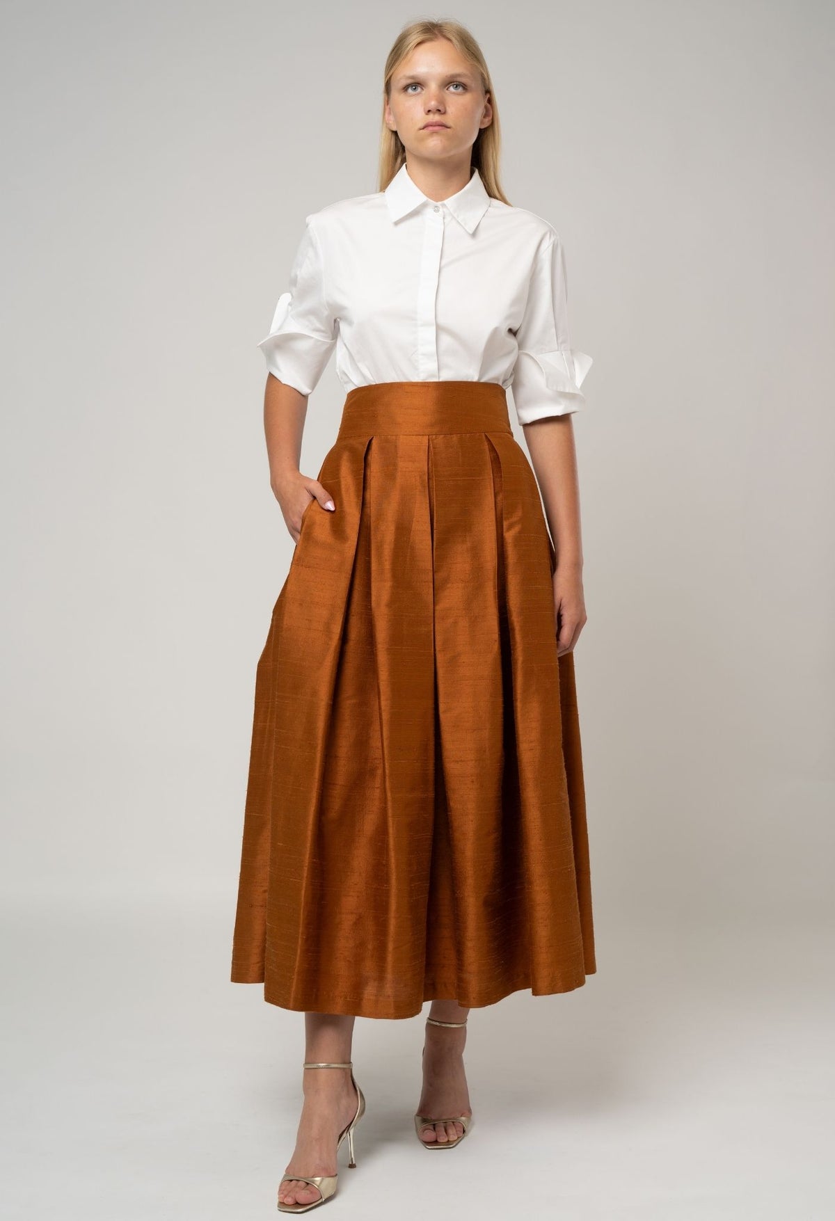 Woman wearing a white blouse and brown skirt on a plain background