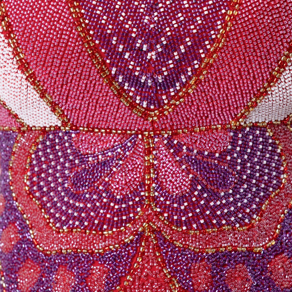 Close-up of the Butterfly Hand-Beaded Embellished Mini Dress by SELF-ADORE, highlighting red, purple, pink, white, and gold beads in symmetrical floral-inspired patterns.