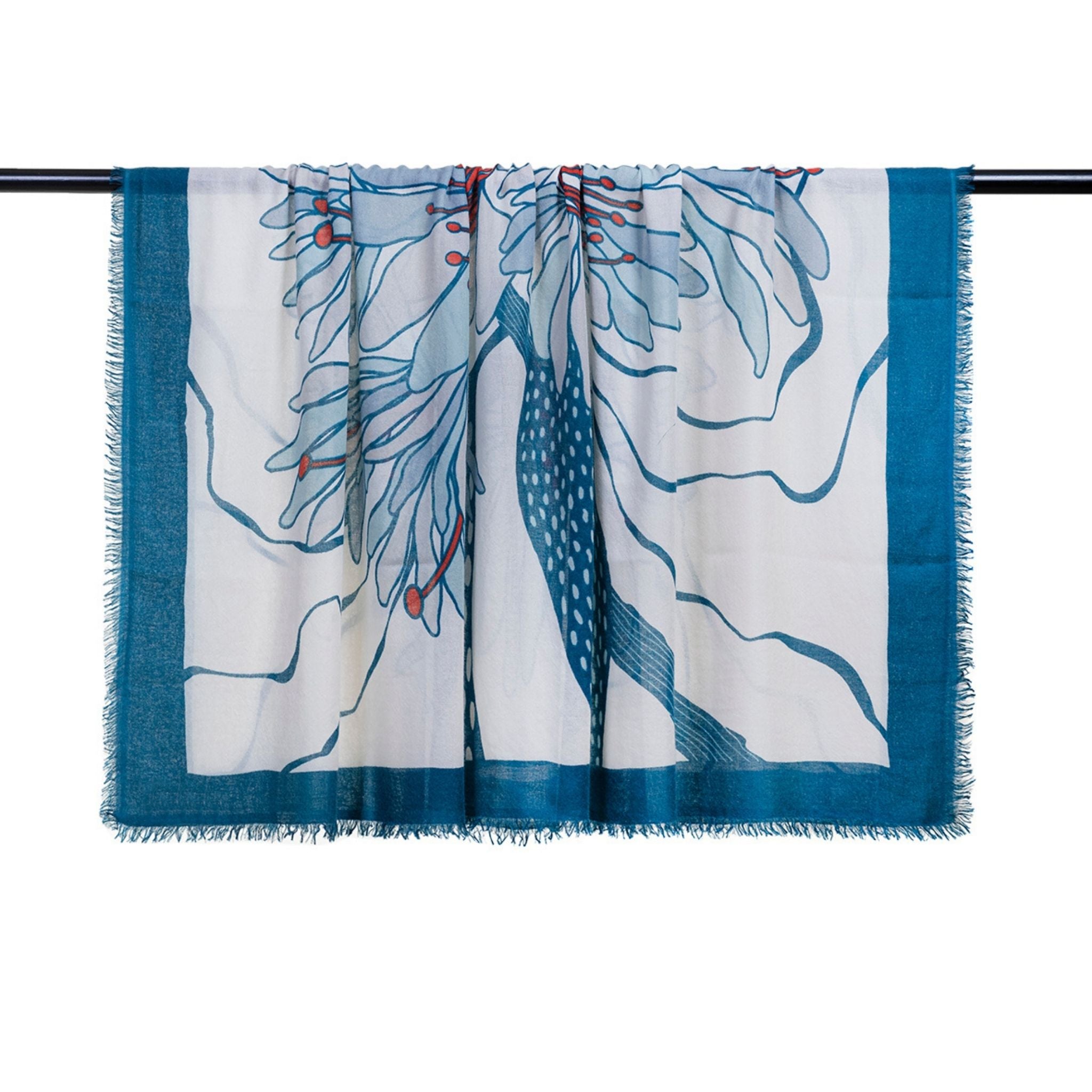 The OO-TO Olympia Printed Square Scarf features a handcrafted abstract botanical design in teal and red tones with a blue border and lightly fringed edges, shown draped over a black rod. Made in Nepal.