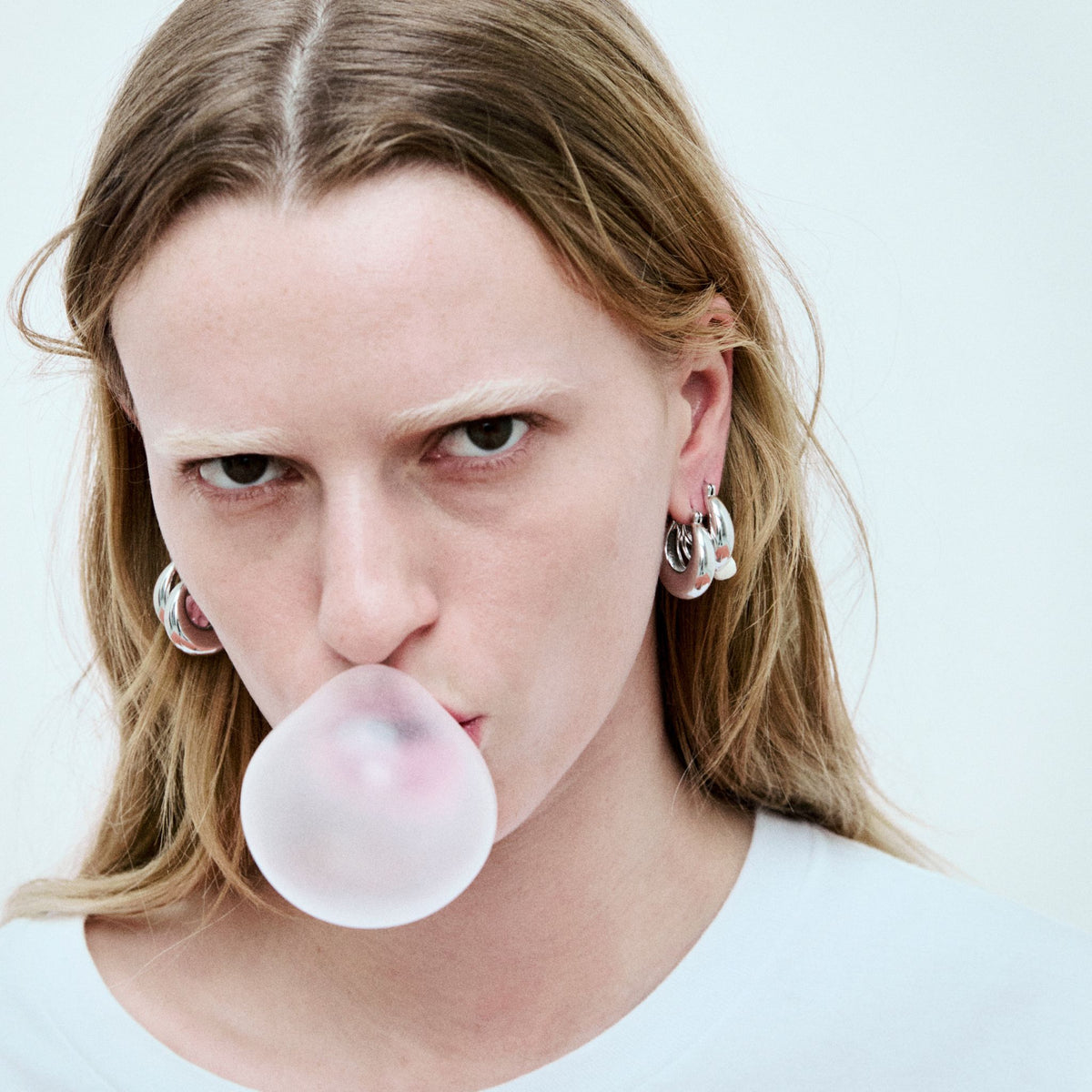 Person blowing a bubble with gum against a plain background