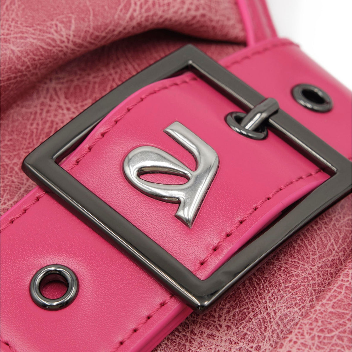 Close-up of a pink leather product with a silver logo and black buckle.