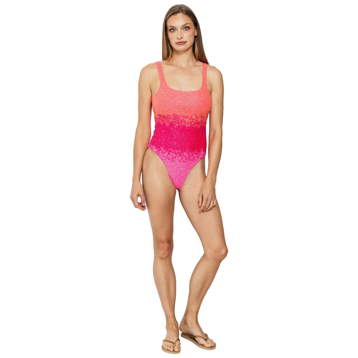 A woman stands facing forward in the SELF-ADORE Ombre Hand-Beaded Embellished One-Piece Swimsuit and beige flip-flops. With long straight hair and a neutral expression, she embodies effortless chic resortwear style.