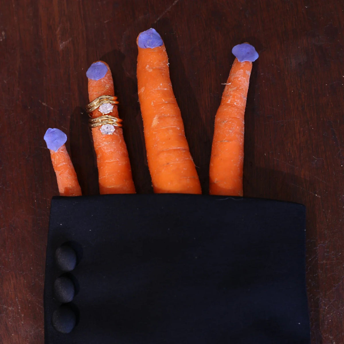 Carrots with blue tips and gold rings on a wooden surface