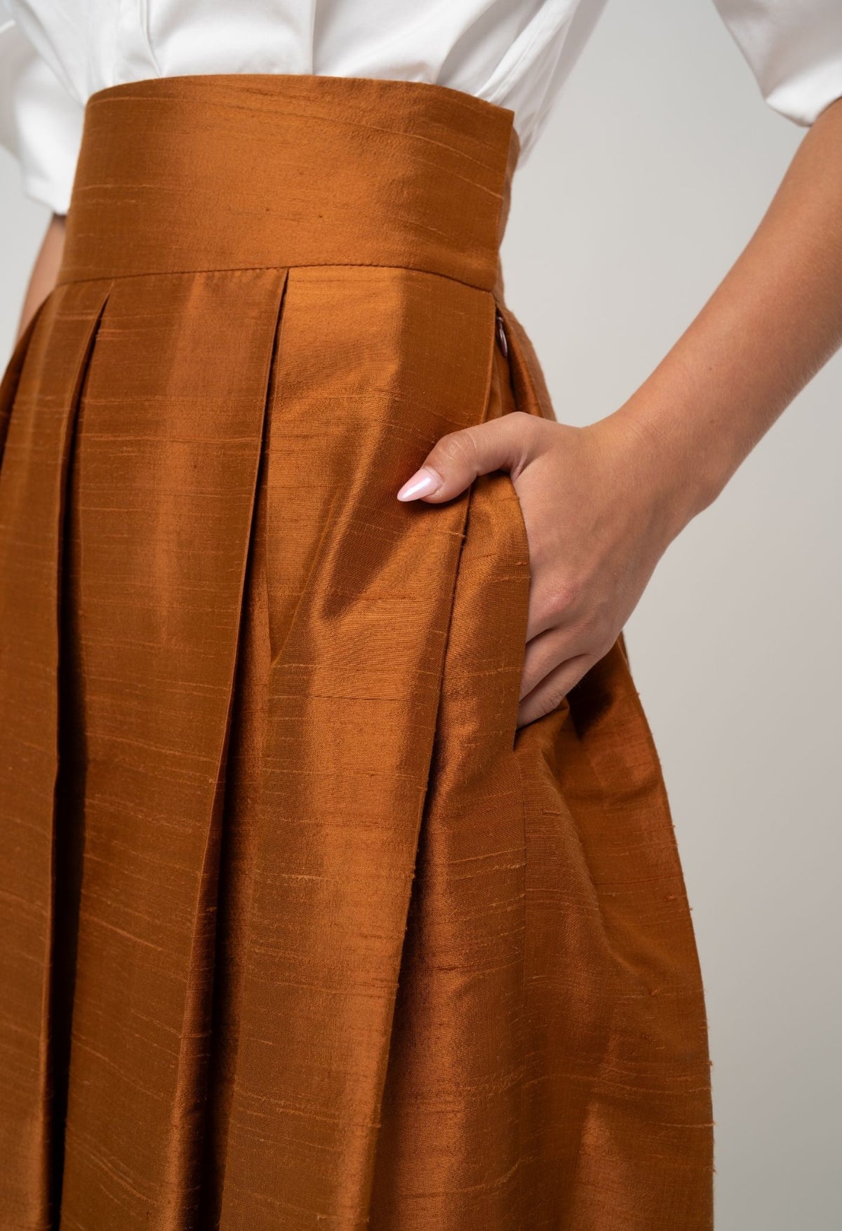 Brown pleated skirt worn by a person on a plain background