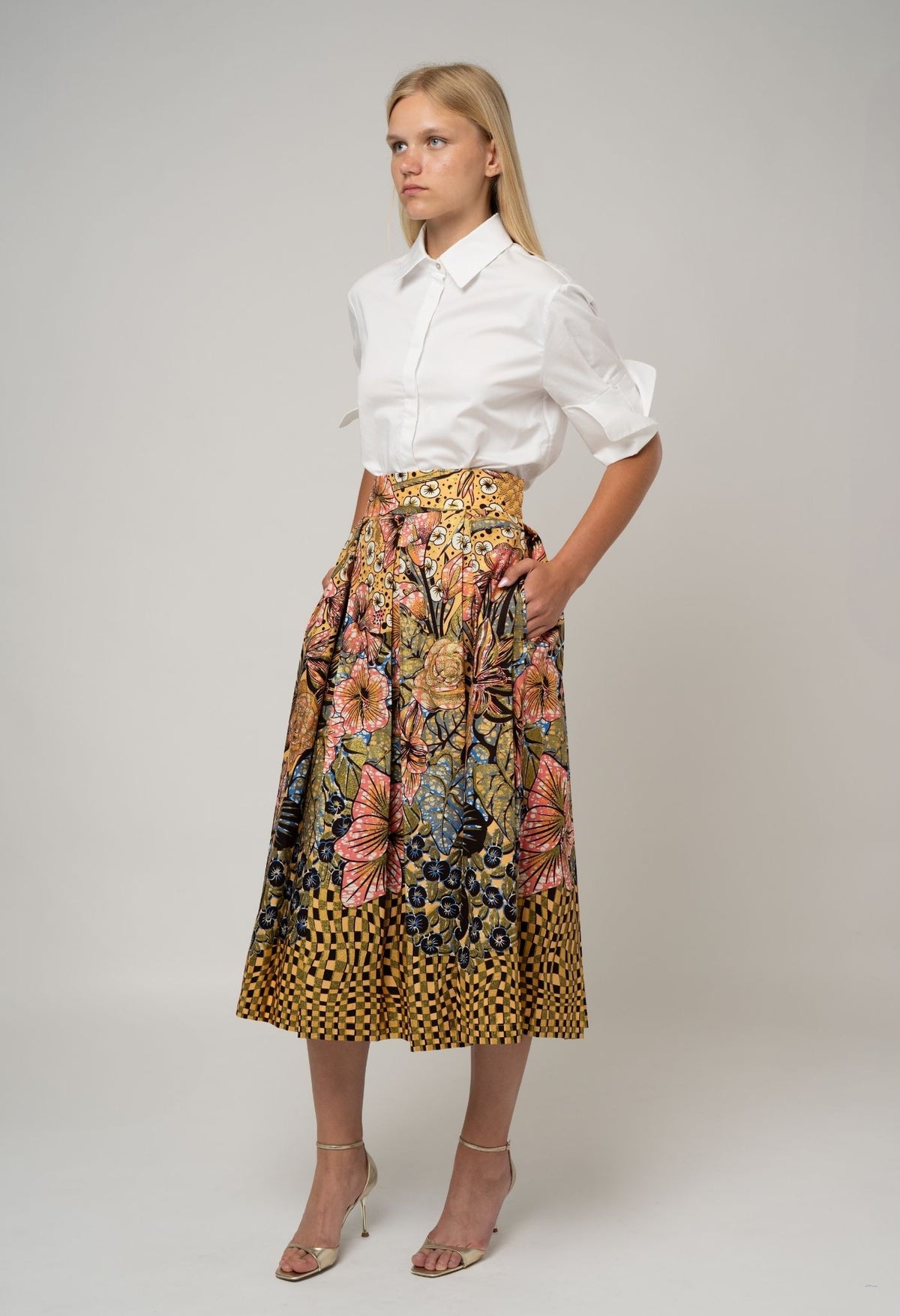 Woman wearing a white blouse and floral skirt on a plain background