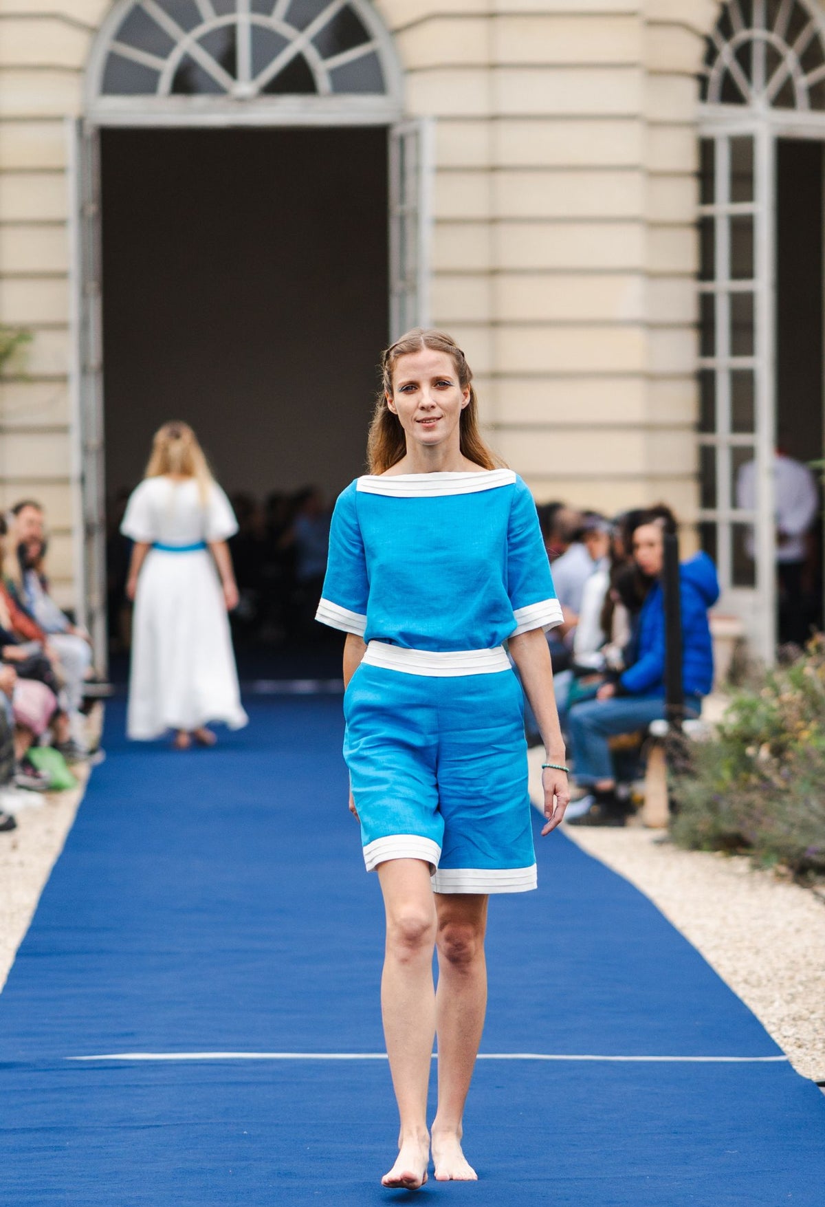 Model wearing turquoise linen top with white trim and short sleeves