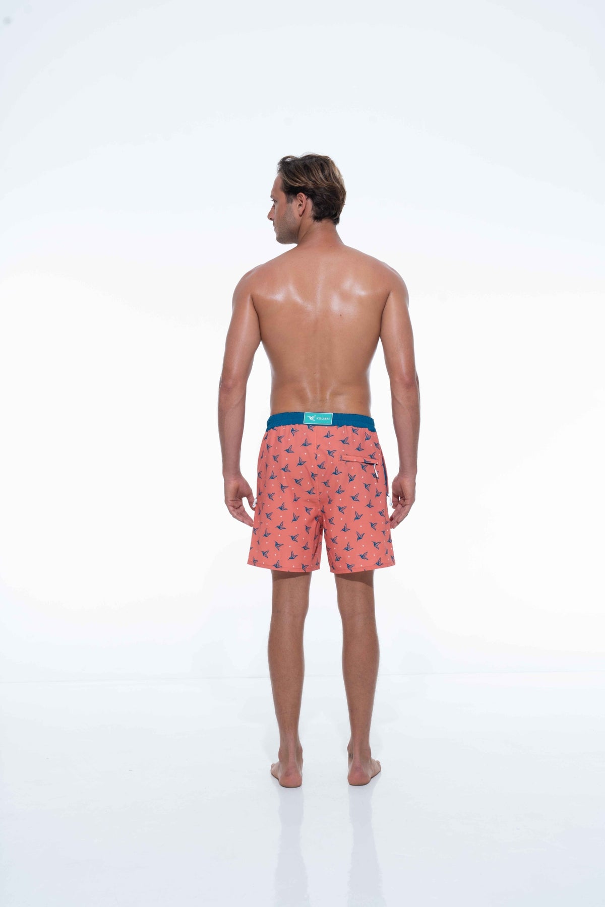 Model wearing Sunset Orange monogram swim trunks